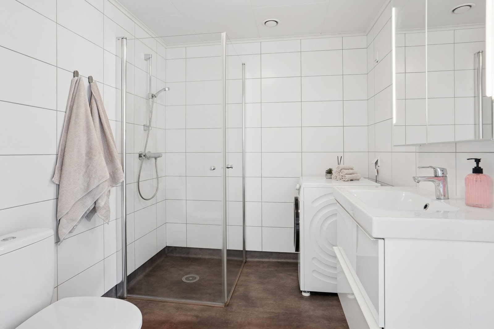 Badet har gulvbelegg og flislagte vegger. Her har du dusjhjørne med vegghengt dusjarmatur. Opplegg for vaskemaskin. Galleribilde