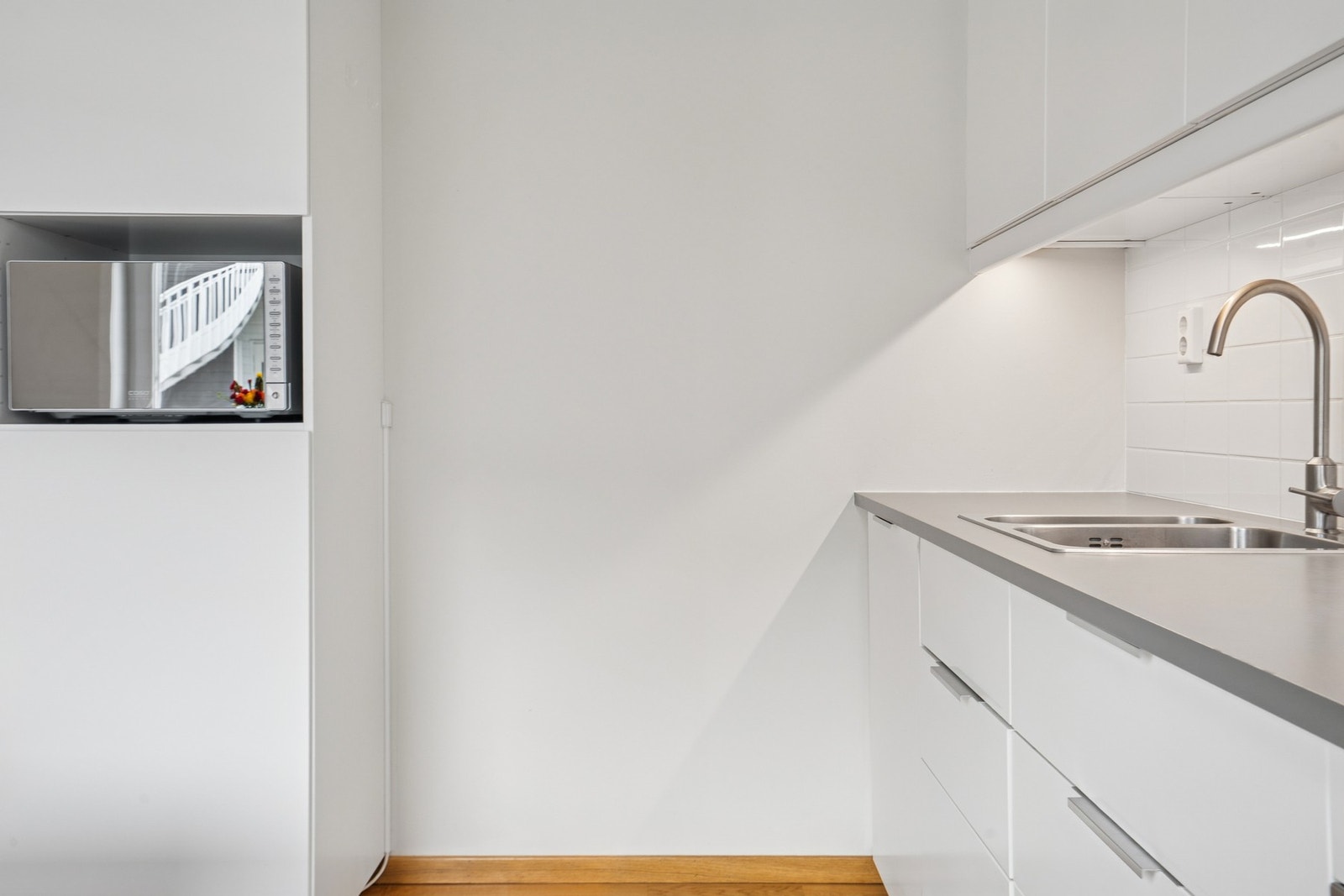 Kjøkkenet har fliser mellom kjøkkenbenk og overskap. Ventilator i overskap som i tillegg driver mekanisk balansert ventilasjon i boligen. Galleribilde