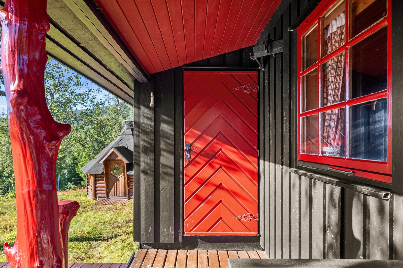 Trivelig inngangsparti med hoveddør malt i samme gjennomførte stil som hyttens eksteriør Galleribilde