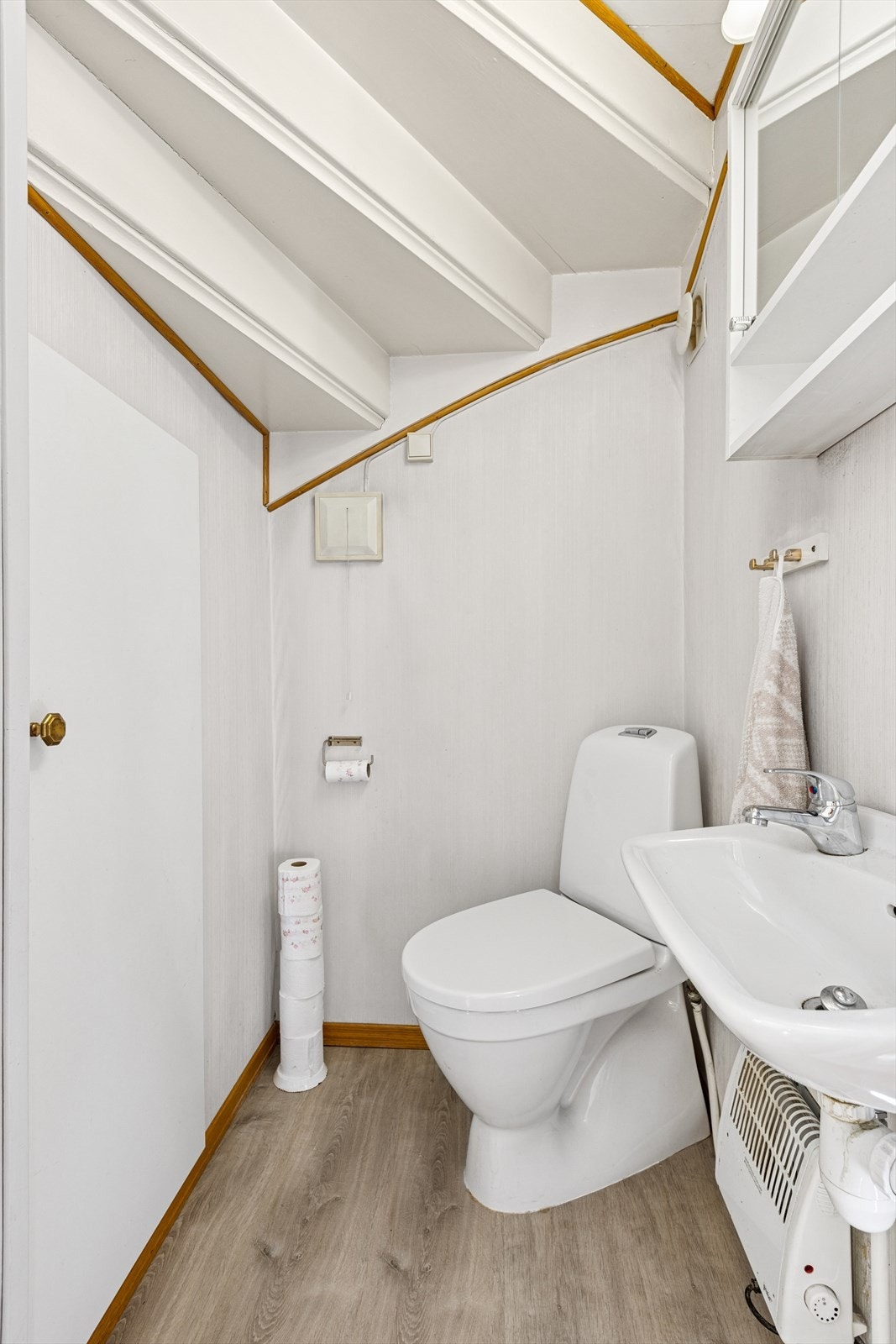 Rommet er utstyrt med en elektrisk styrt avtrekksvifte montert i ytterveggen. Det gulvstående toalettet er fra 2024, og rommet har også en praktisk servant og veggskap med speilfronter. Galleribilde