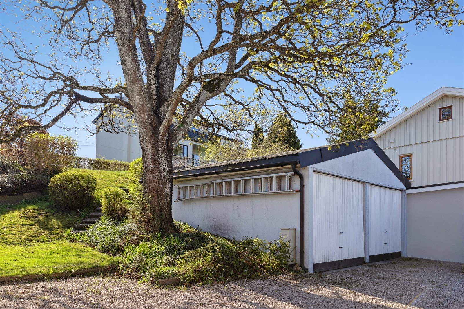 Dobbelgarasje med kjøreadkomst via garasjeporter i trekonstruksjon, hvorav den ene porten er elektrisk styrt. Praktisk og funksjonell løsning for enkel parkering og tilgang. Galleribilde