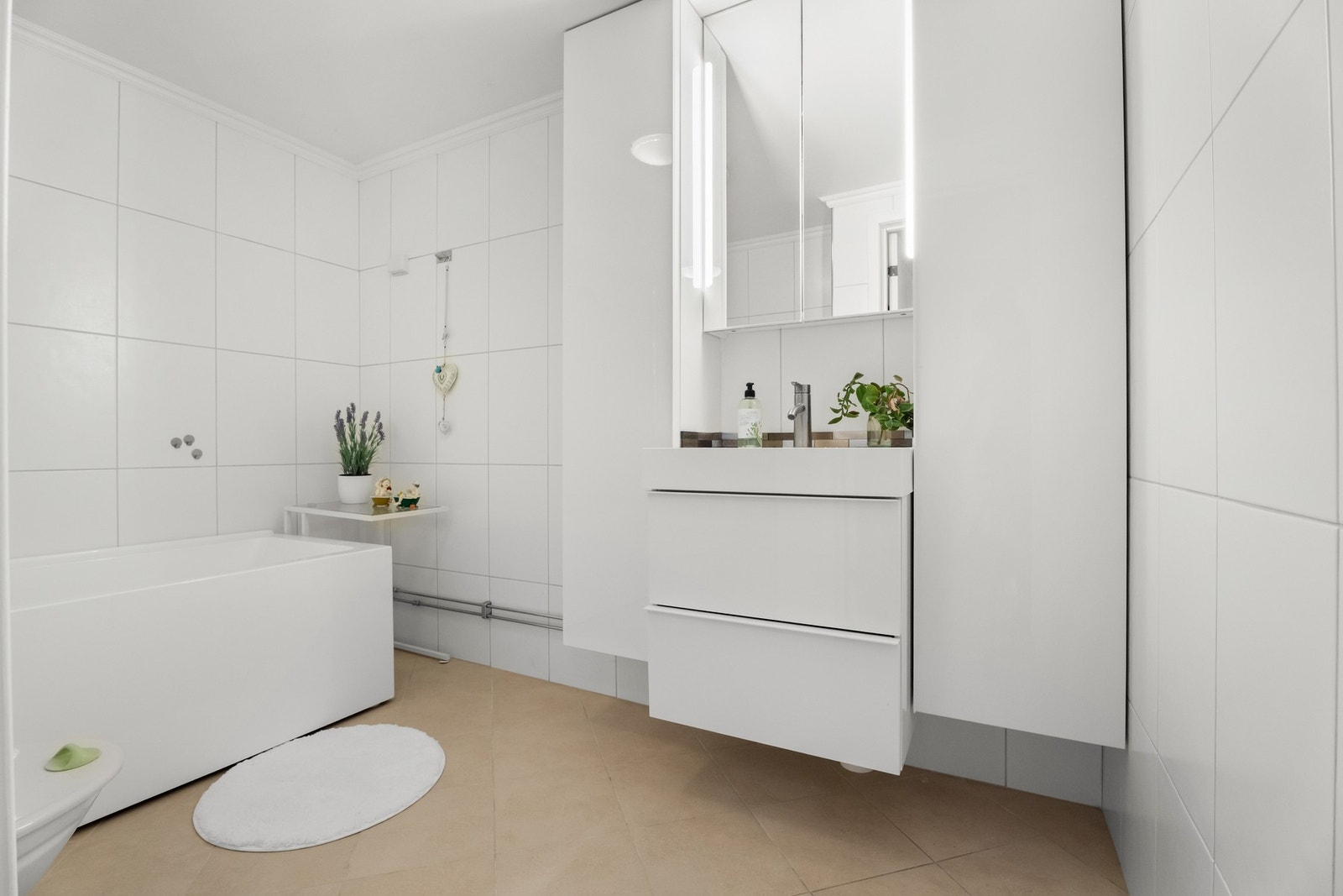 Hvite fliser på veggene og sandfargede fliser på gulv med gulvvarme. Galleribilde