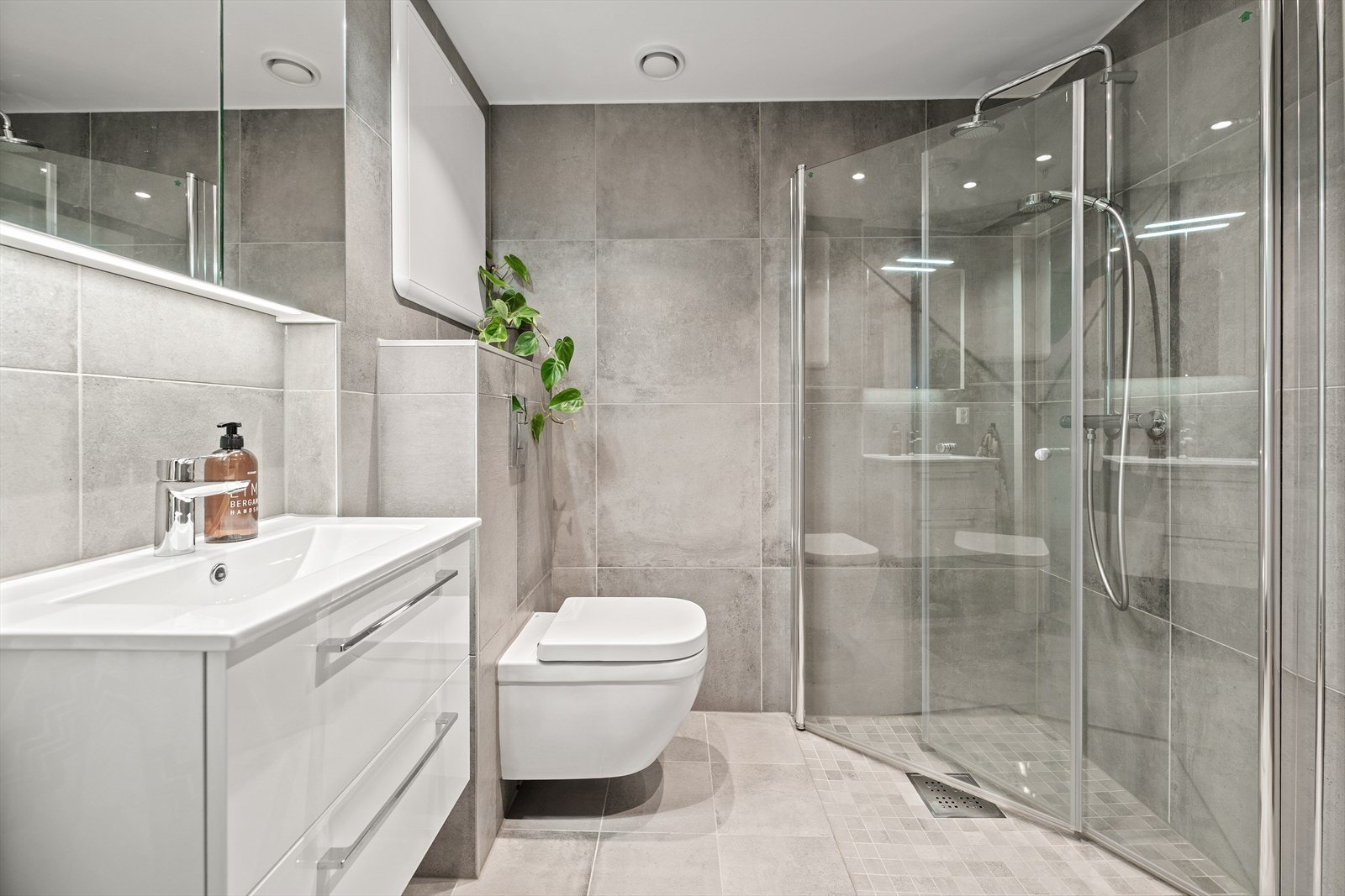 Badet er utstyrt med innredning bestående av nedfelt servant med underskuff og 1-greps blandebatteri, speil, dusjhjørne med glassdører, vegghengt toalett og teknisk skap for vannrør. Downlights. Galleribilde