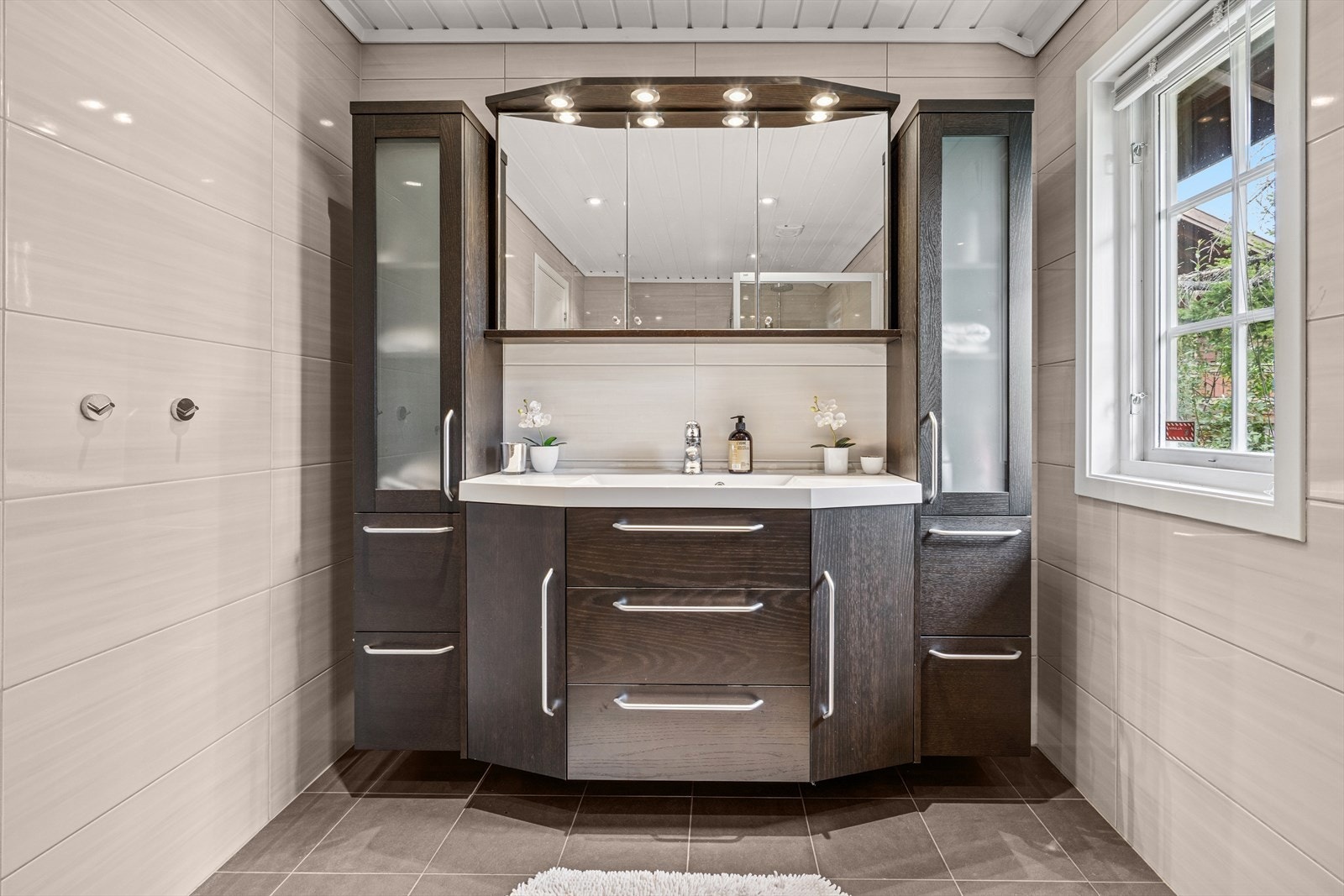 Badet er innredet med nedfelt servant og har rikelig med skapplass Galleribilde