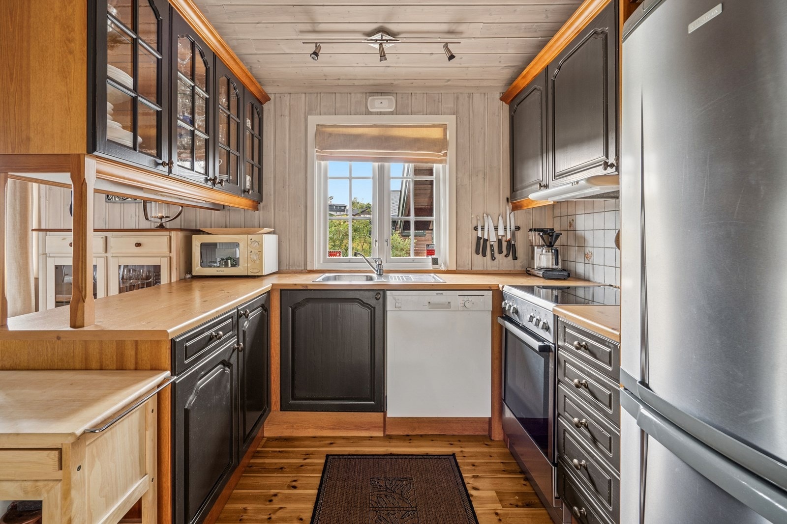 Kjøkkenet er innredet med profilerte fronter og benkeplate av laminat. Det er montert fliser mellom over- og underskap på en vegg Galleribilde