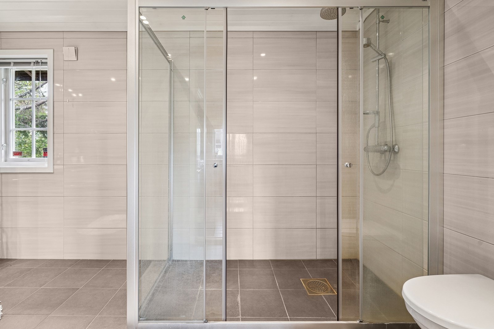 Romslig dusjhjørne og veggmontert toalett Galleribilde