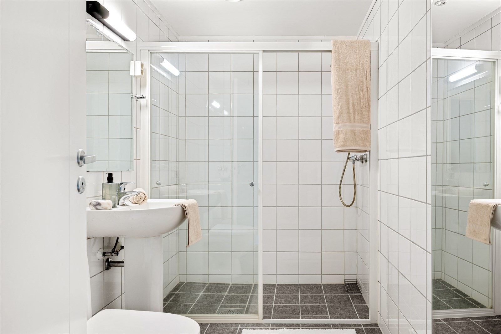 Bad med fliser på gulv og vegger. Badet er innredet med stor dusj, toalett og vask. Galleribilde