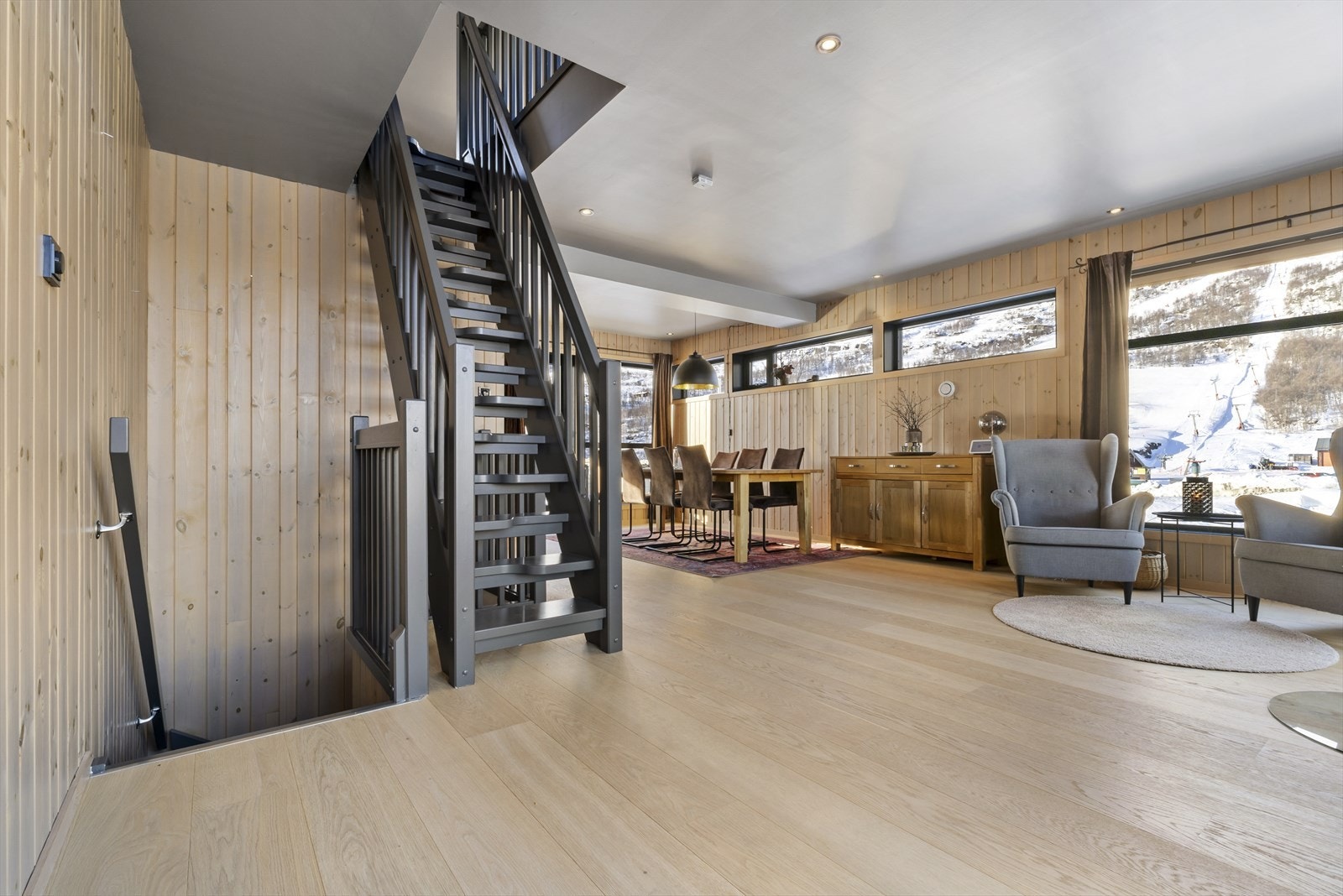 Lys og romslig stue med store vinduer som gir flott utsikt over naturen Galleribilde