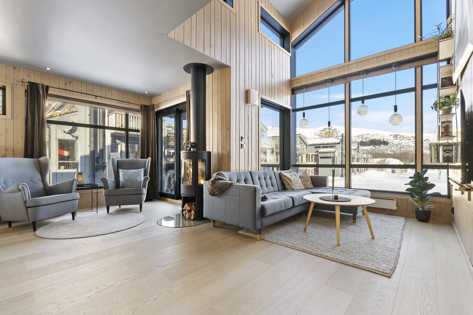 Åpen stue med generøs takhøyde og naturlig lys som gir rommet en luftig følelse Galleribilde