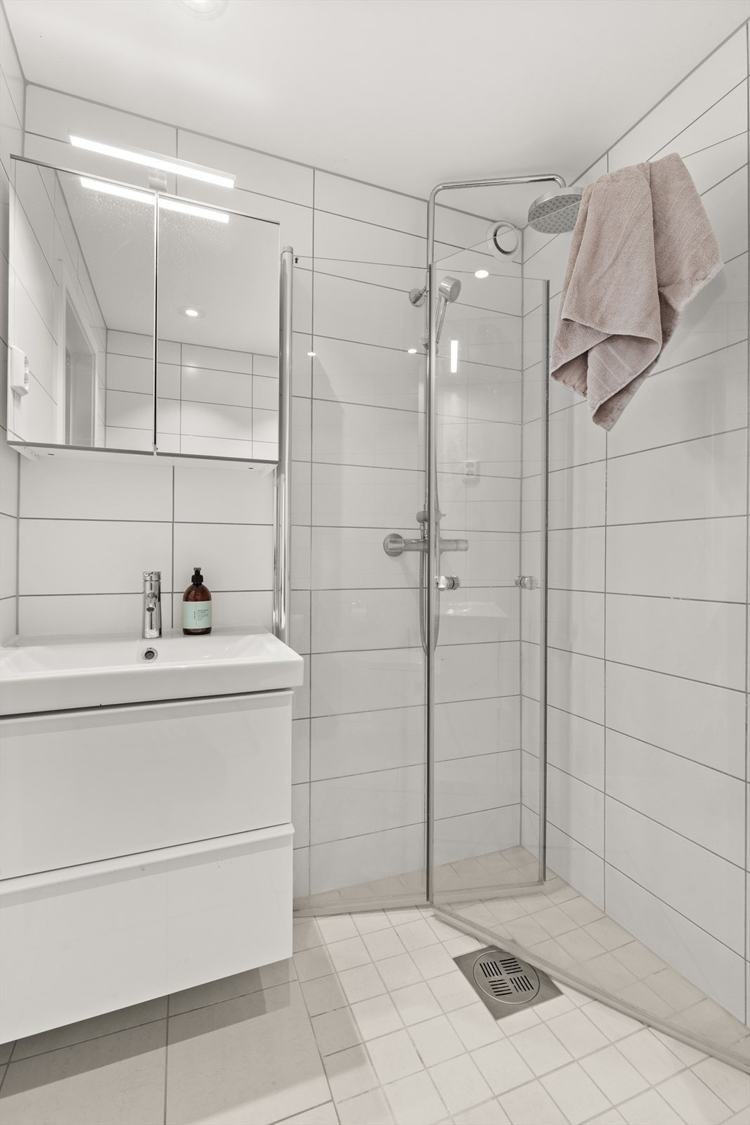 Badet er innredet med vegghengt klosett, servant nedfelt i innredning, speilskap og dusjhjørne med svingbare glassdører. Galleribilde