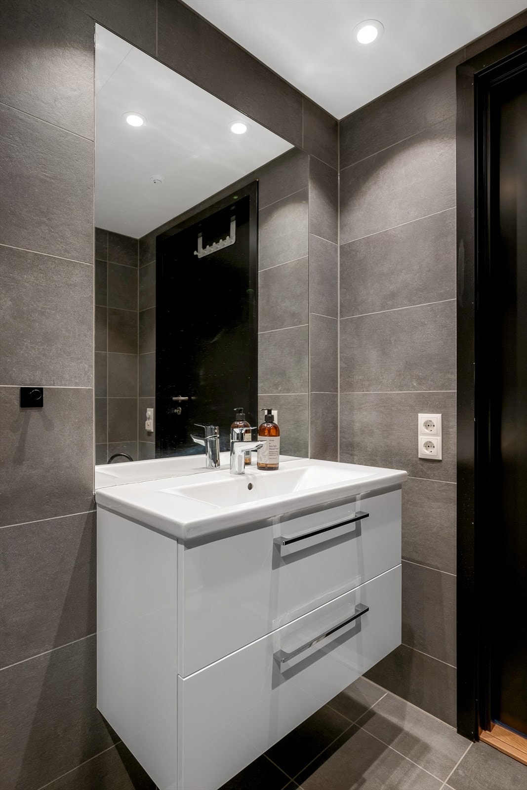 Badet inneholder vegghengt toalett, servantskap med to skuffer, opplegg for vaskemaskin og dusjhjørne. Galleribilde