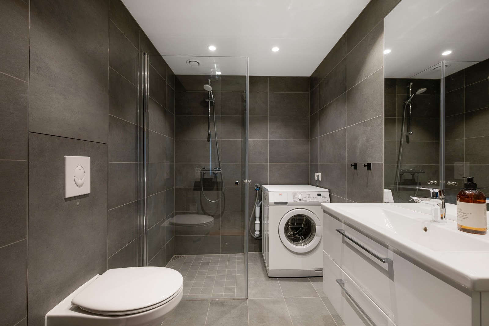 Badet er helfliset med grå fliser på gulv og vegger. Innredningen er i hvit utførelse med detaljer i krom. Et tidløst og klassisk uttrykk. Galleribilde