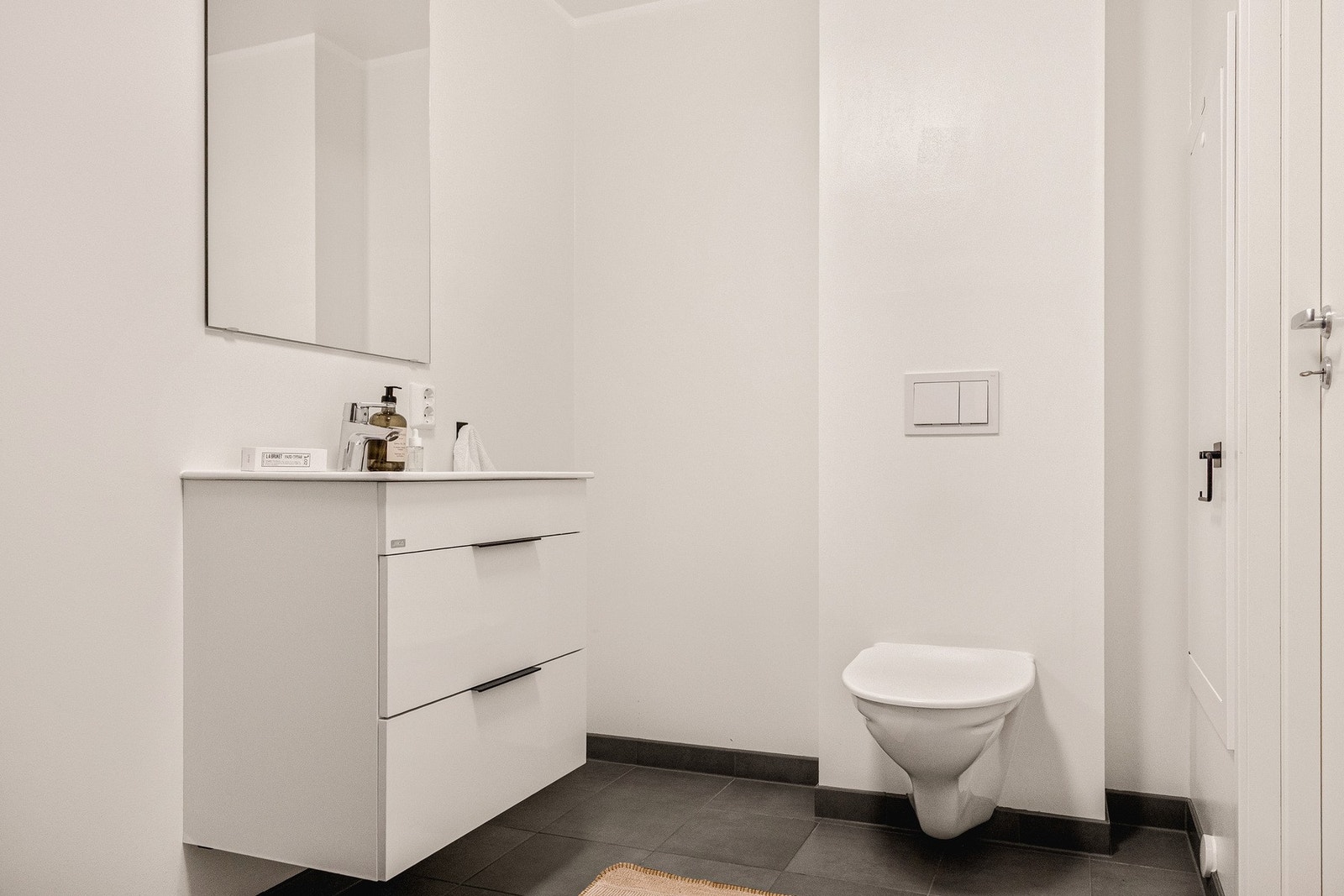 Det er innredet med vegghengt toalett, dusjhjørne med dusjgarnityr og baderomsmøblement med servant og speil. Galleribilde