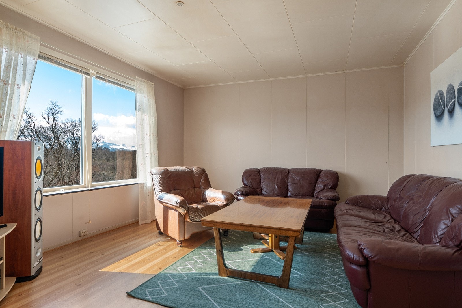 Stue med gode lysforhold og utsyn mot grønne omgivelser - her ligger alt til rette for å skape et lunt og trivelig oppholdsrom