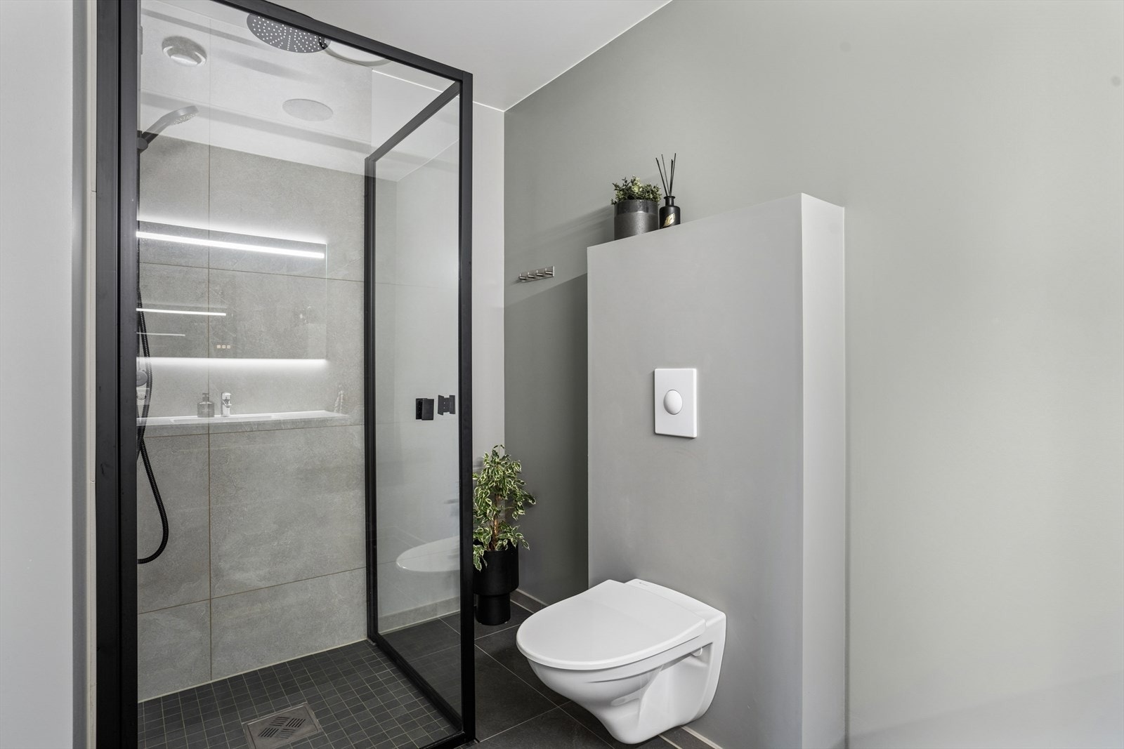 Badet har flislagt gulv, fliser på vegg i dusj, og ellers malte overflater på vegger. Galleribilde