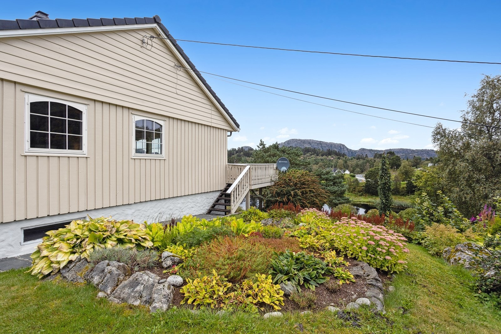 Tomten er opparbeidet med betongtrapp, plen, prydbusker, frukttrær, blomsterbed, hekk, forstøtningsmurer, kantmurer, skiferheller, gruset innkjørsel og parkering Galleribilde