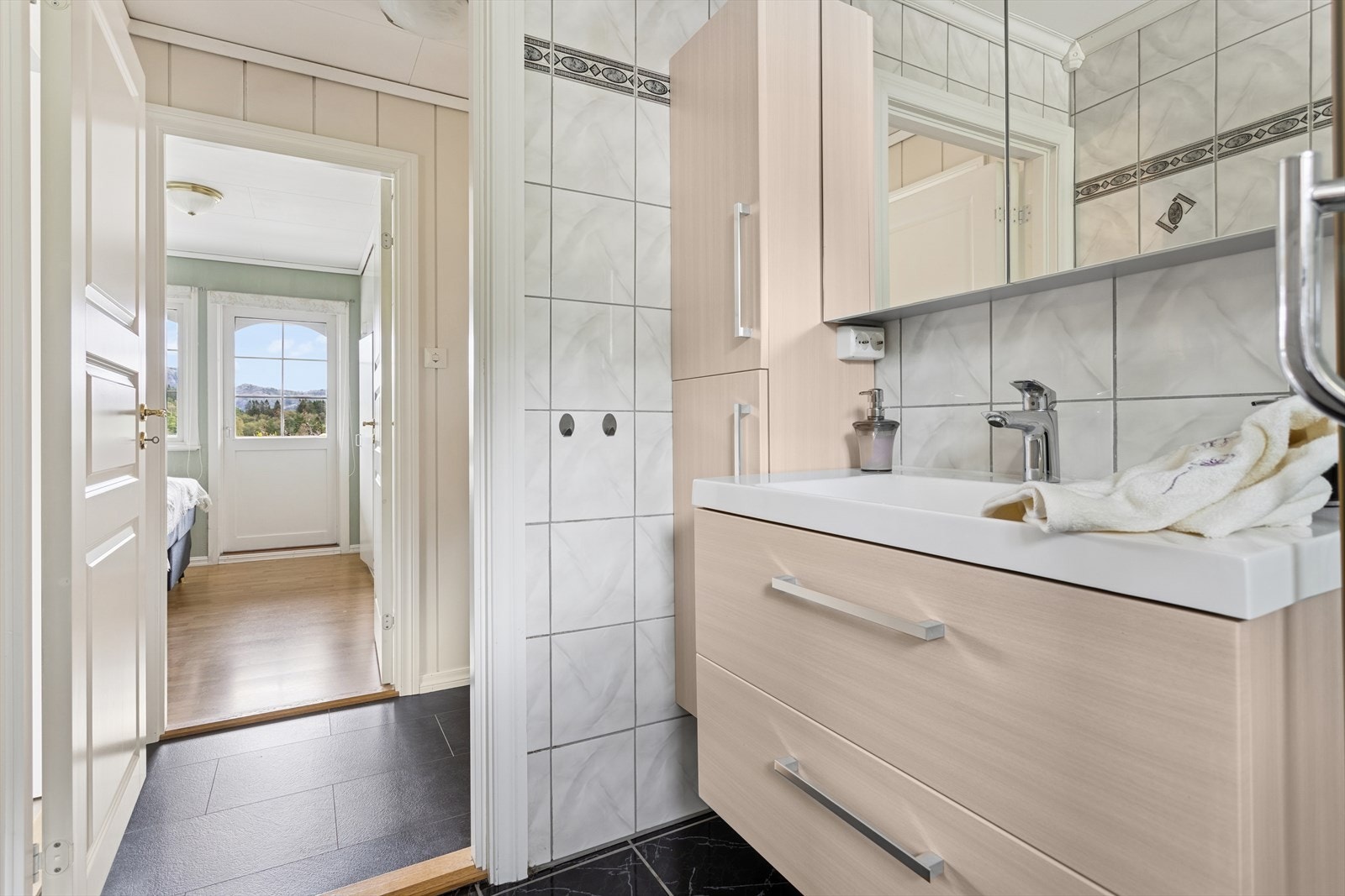 Badet i første etasje ligger i enden av gangen og har flislagte vegger og gulv med varmekabler Galleribilde