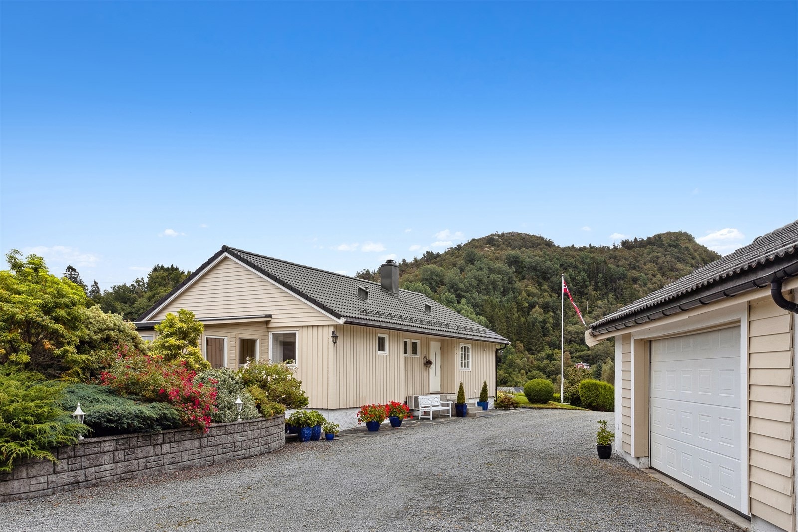 Stor og romslig gruset tomt med velstelte grøntarealer - ideell for både parkering, lek og hagebruk Galleribilde