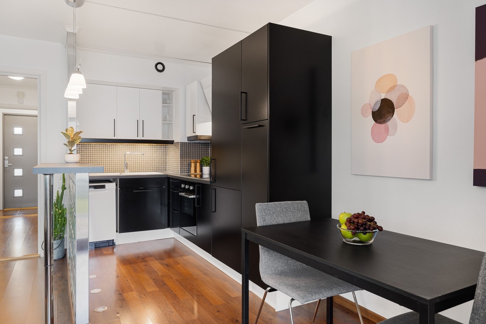 Kjøkken i vinkelløsning med innredning fra IKEA. Underskap og høyskap med svarte, glatte fronter og overskap med hvite, glatte fronter. Galleribilde