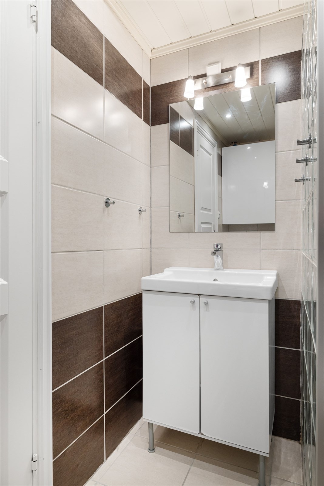 Badet har servantskap med heldekkende servant og speil med lys i overkant. Galleribilde