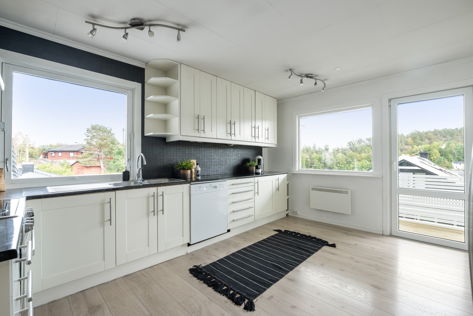 Innredningen er fra 2004, med hvite, profilerte fronter, dobbel oppvaskkum og mørk benkeplate av laminat. Galleribilde