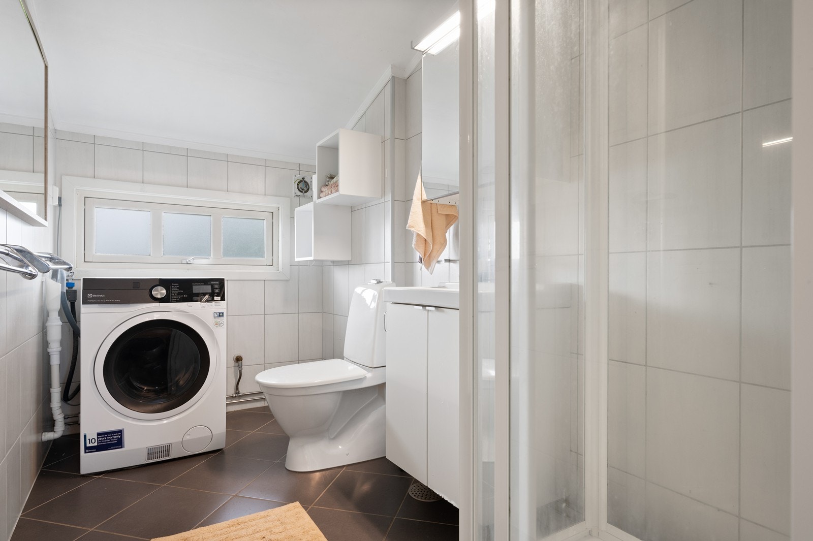Baderommet i 1.etasje har opplegg for vaskemaskin og er innredet med nedfelt servant, toalett og dusjkabinett. Galleribilde