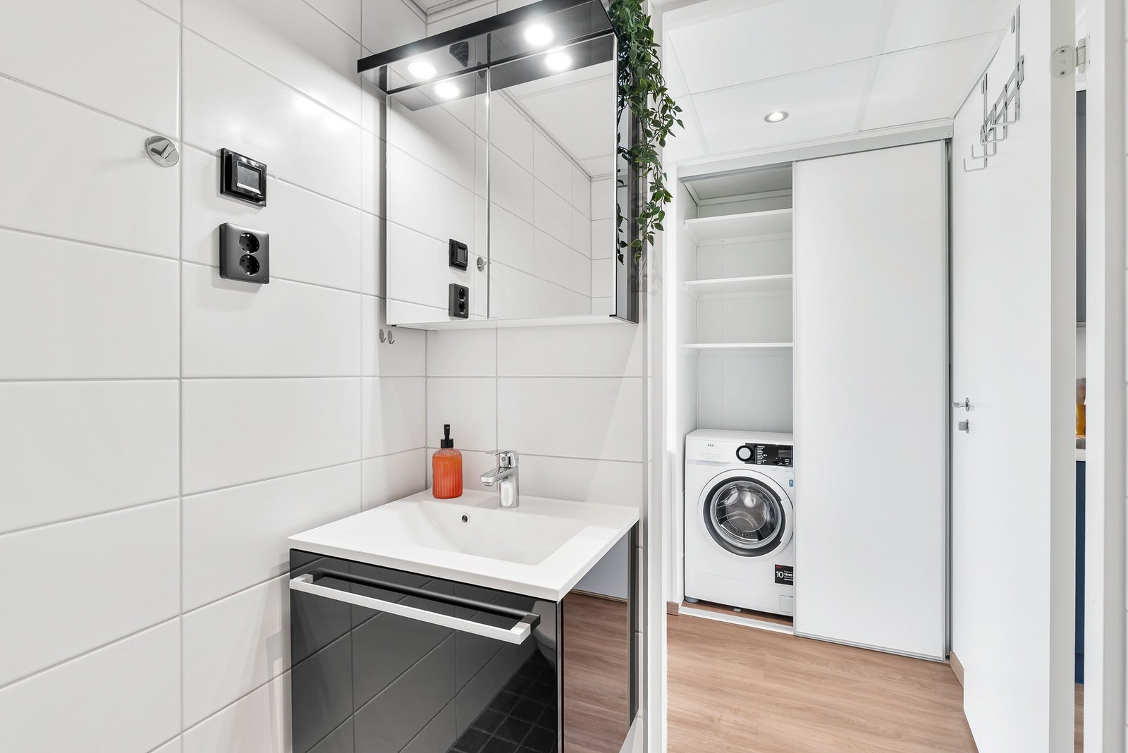 Servantinnredning med speilskap m/innfelte spotter over. Opplegg for vaskemaskin i skyvedørsgarderobe i gangen. Galleribilde