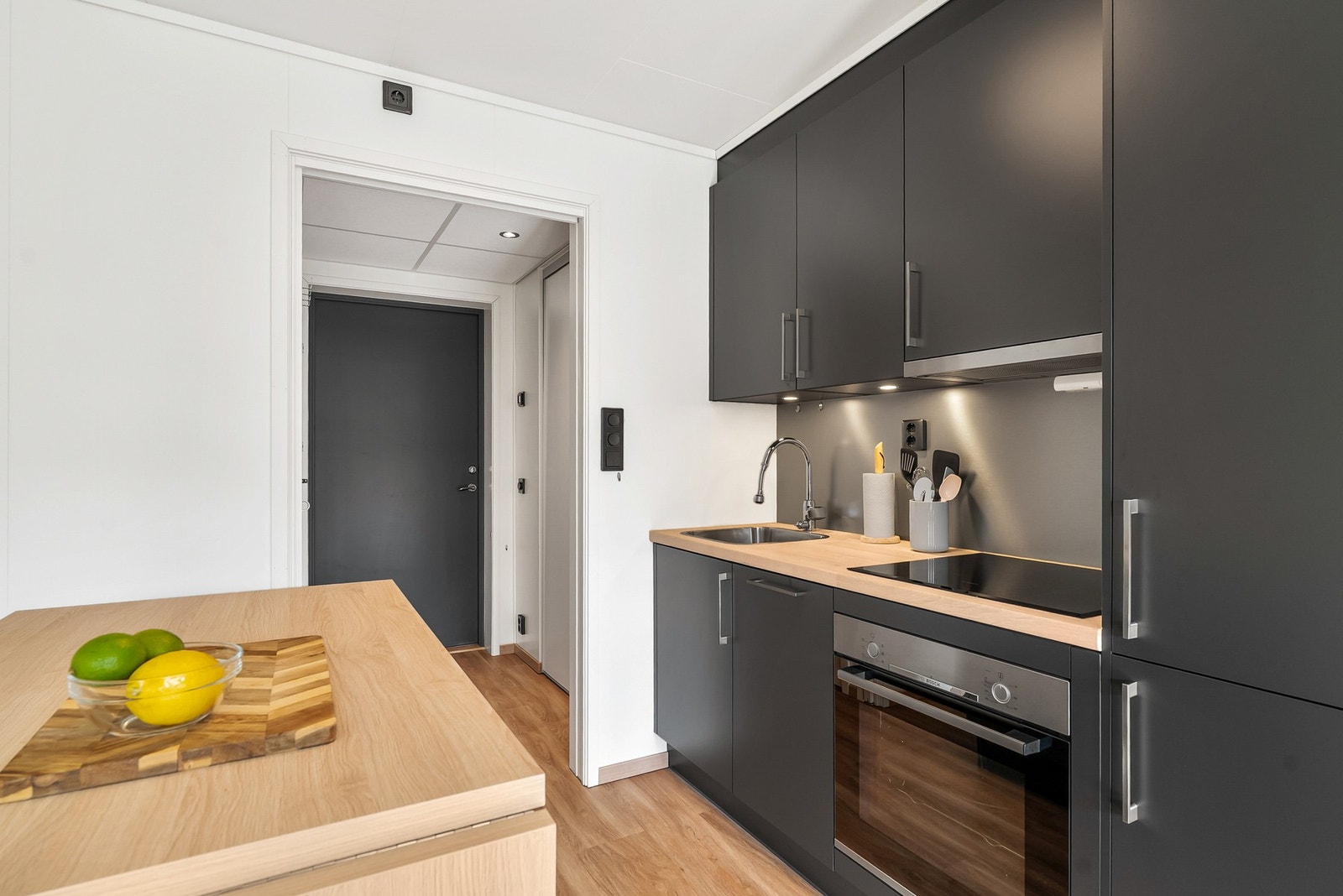 Lekkert kjøkken med slette grå fronter og lys benkeplate av laminat. Downlights under overskap. Galleribilde