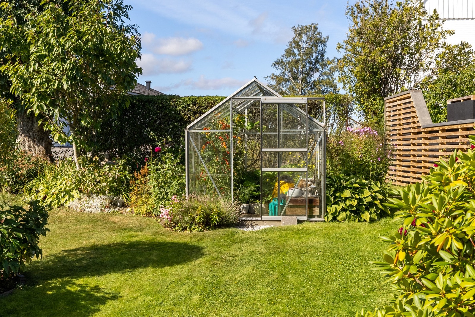 Hagen er pent opparbeidet med flotte planter og drivhus. Her vokser det tomater til den store gullmedalje. Galleribilde
