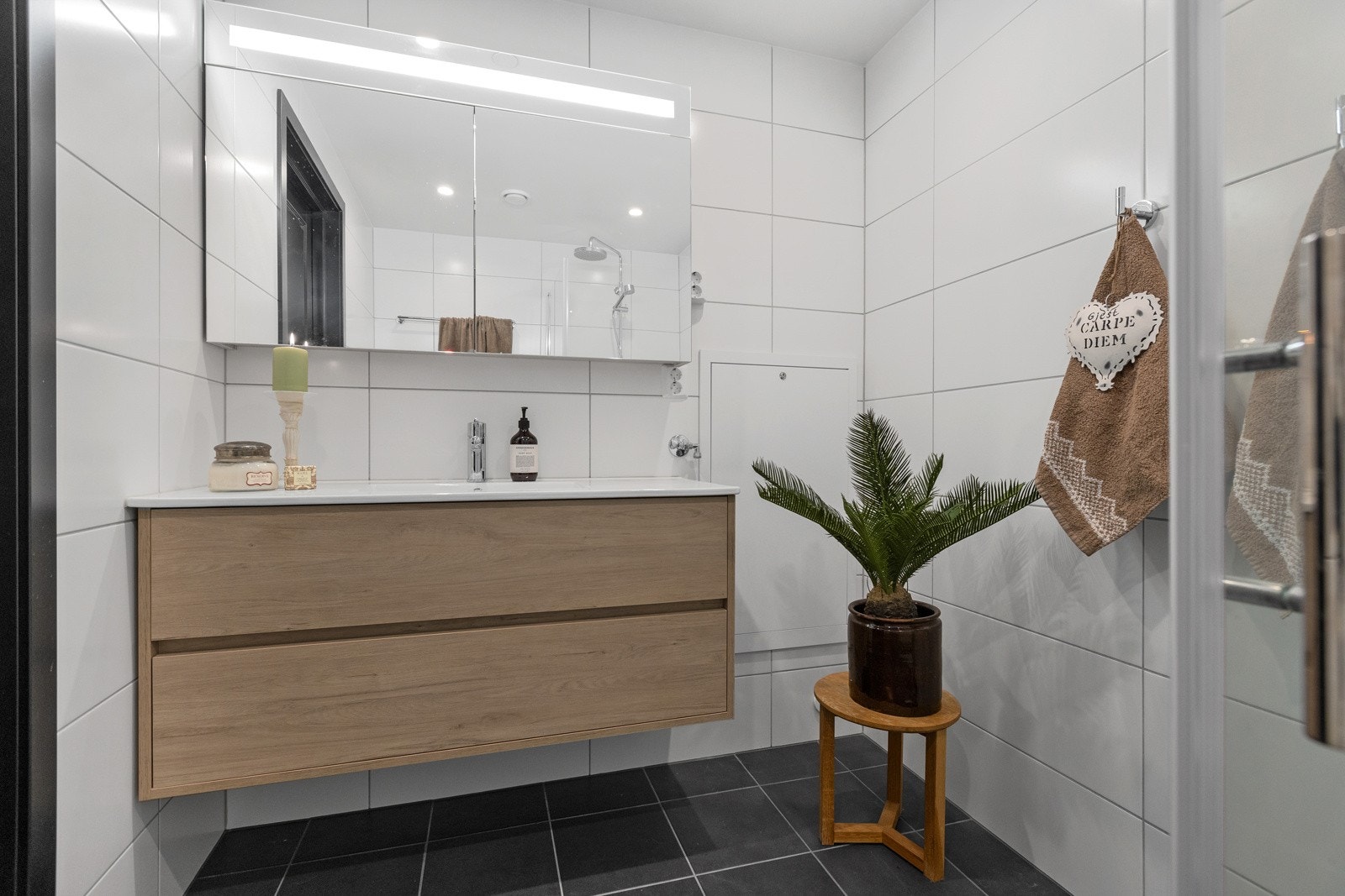 Badet er innredet med servantskap, speilskap, dusjvegger og vegghengt toalett Galleribilde