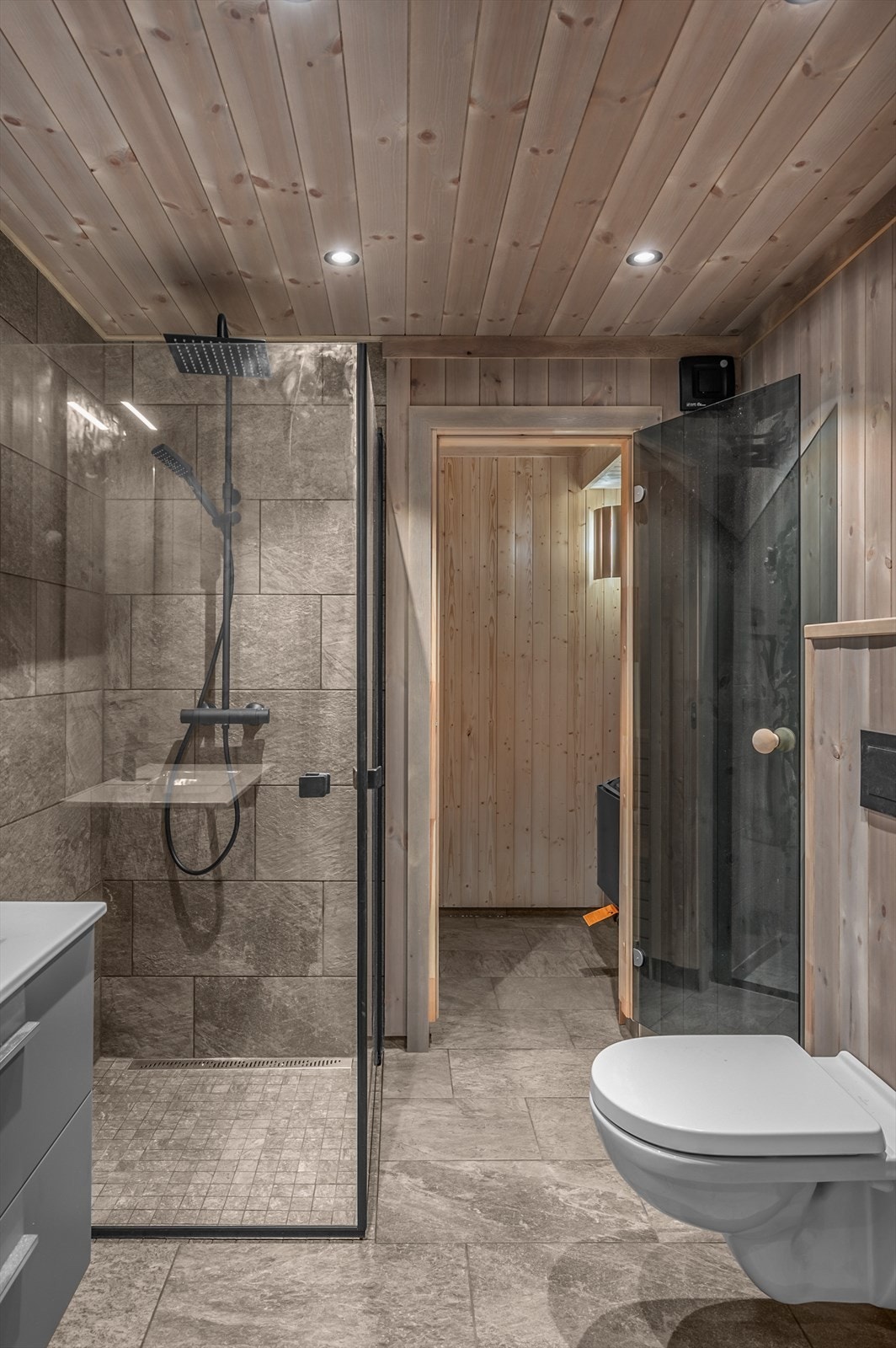 Hovedbad med dusjhjørne, vegghengt toalett, servantinnredning og badstue. Galleribilde