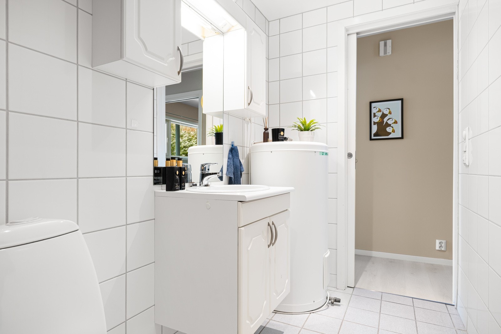 Det 4,6 kvm store badet er flislagt med behagelig gulvvarme. Innredningen består av nedfelt servant med underskap, toalett, opplegg for vaskemaskin og dusjhjørne. Galleribilde