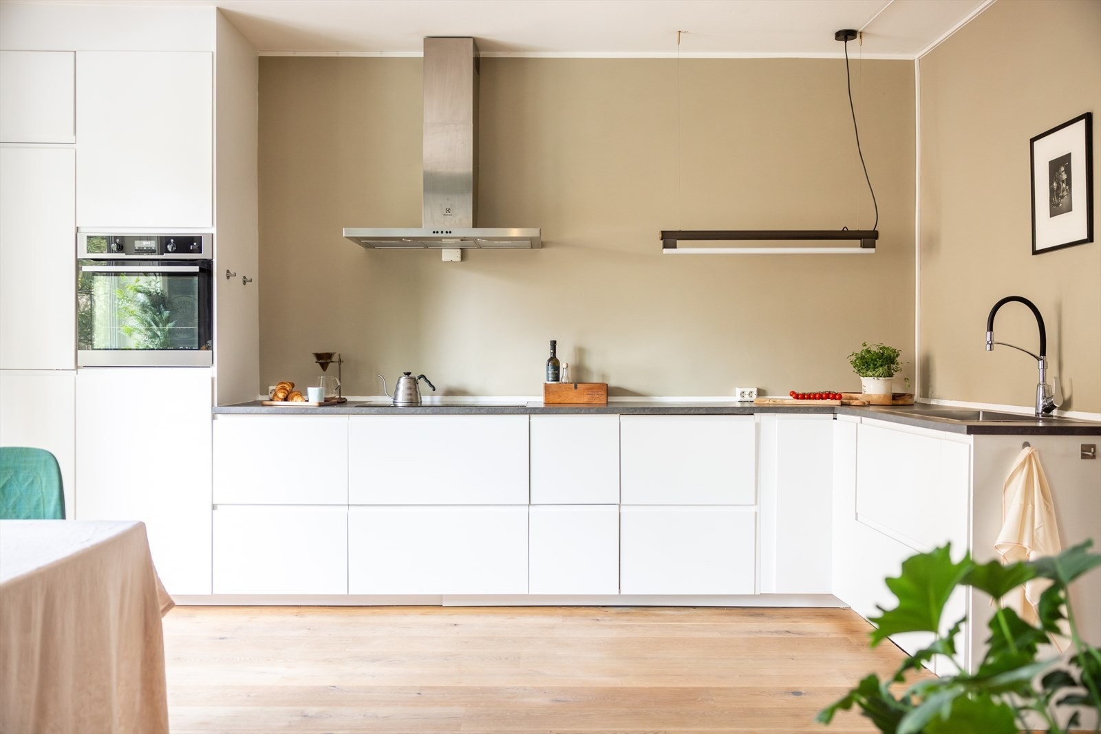 Kjøkkenet har et moderne preg og består av hvite, glatte fronter og benkeplate av laminat med nedfelt vaskekum. Galleribilde