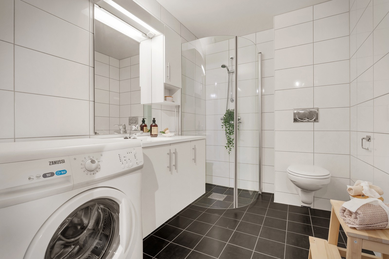 Badet er pent helfliset og holder en suveren standard. Her er det innredet med vegghengt toalett, dusj og heldekkende servant med belyst speil over. Galleribilde