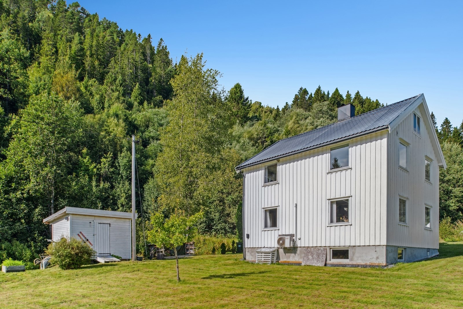 Flat, lett skrånende eiendomstomt (1 579 m²) utlagt med plen, busker og diverse trær. Galleribilde