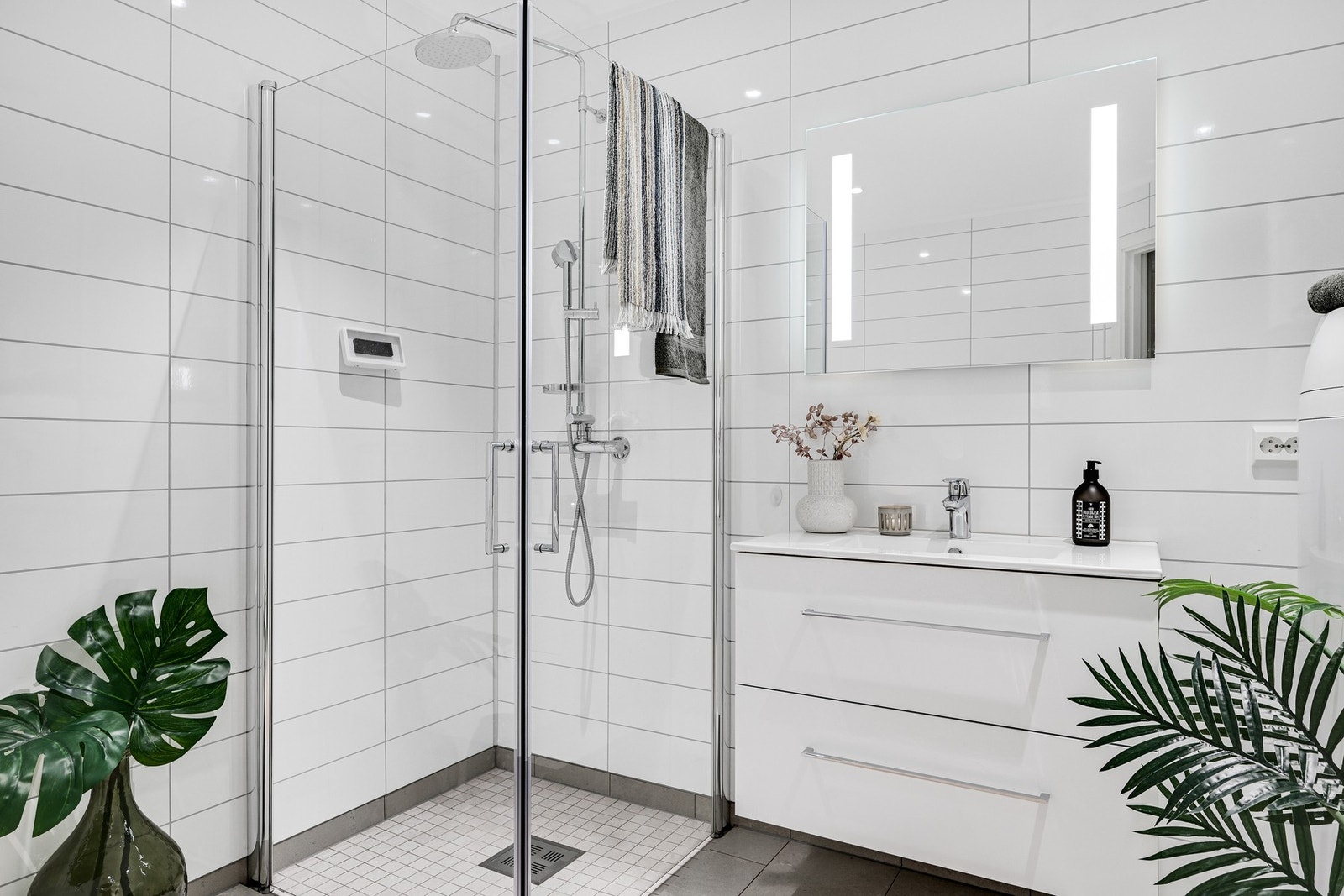 Badet har gulvvarme og inneholder servant med skuffer, speil med lys, veggmontert wc og dusjhjørne. Galleribilde