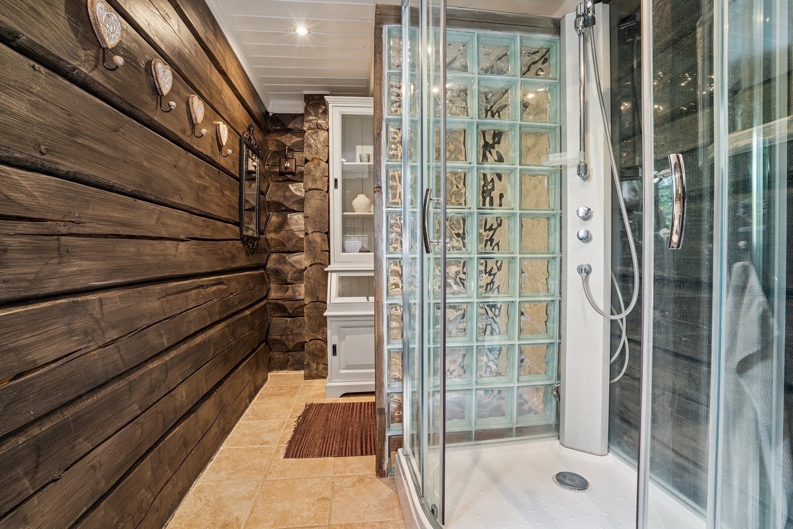 Det har flislagt gulv, vegger har fliser og tømmer og himling har panel. Det er elektriske varmekabler på deler av gulvet Galleribilde