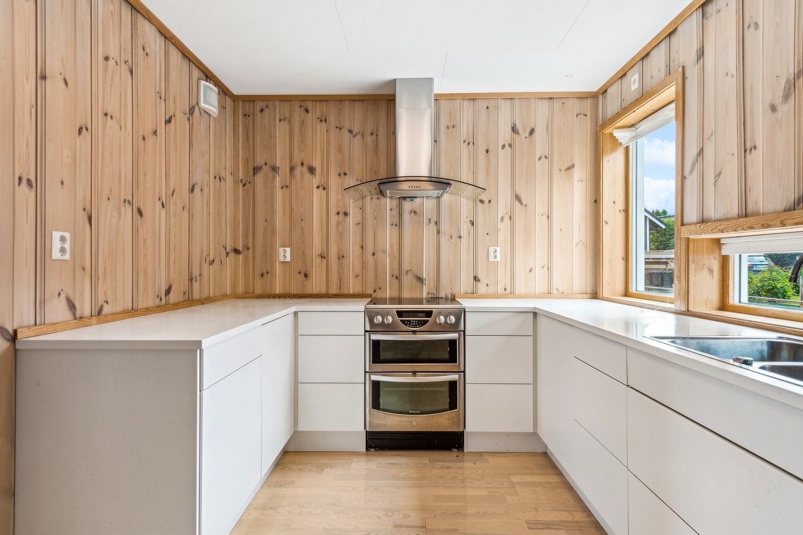 Her finner du en pen og stilren innredning med glatte, hvite fronter og en lys laminat benkeplate med dobbel kum. Galleribilde