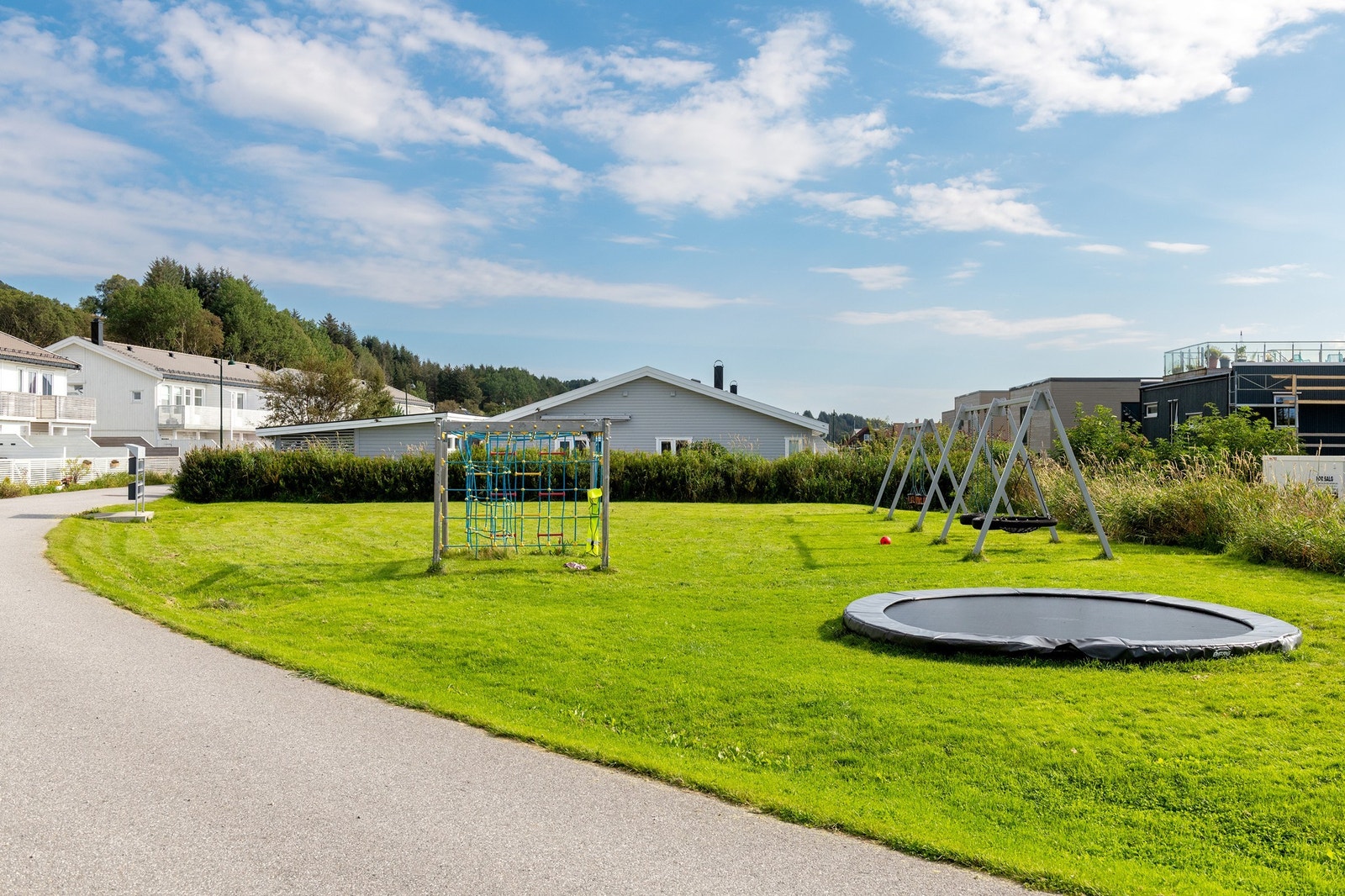 Lekeplass i nabolaget med trampoline og klatrestativ. Galleribilde