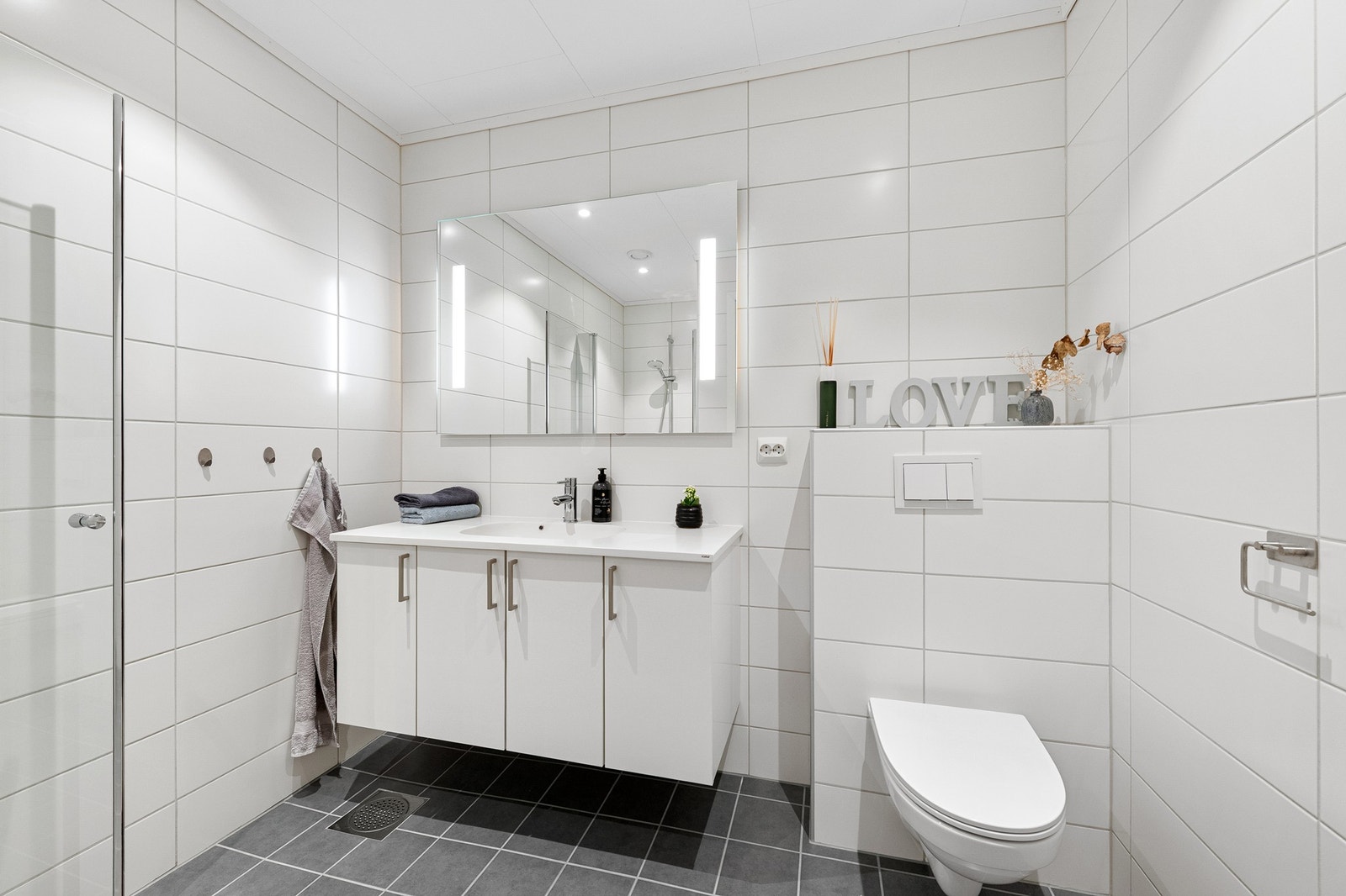 Flislagt bad i 1. etasje med dusj, servantinnredning og vegghengt toalett. Galleribilde