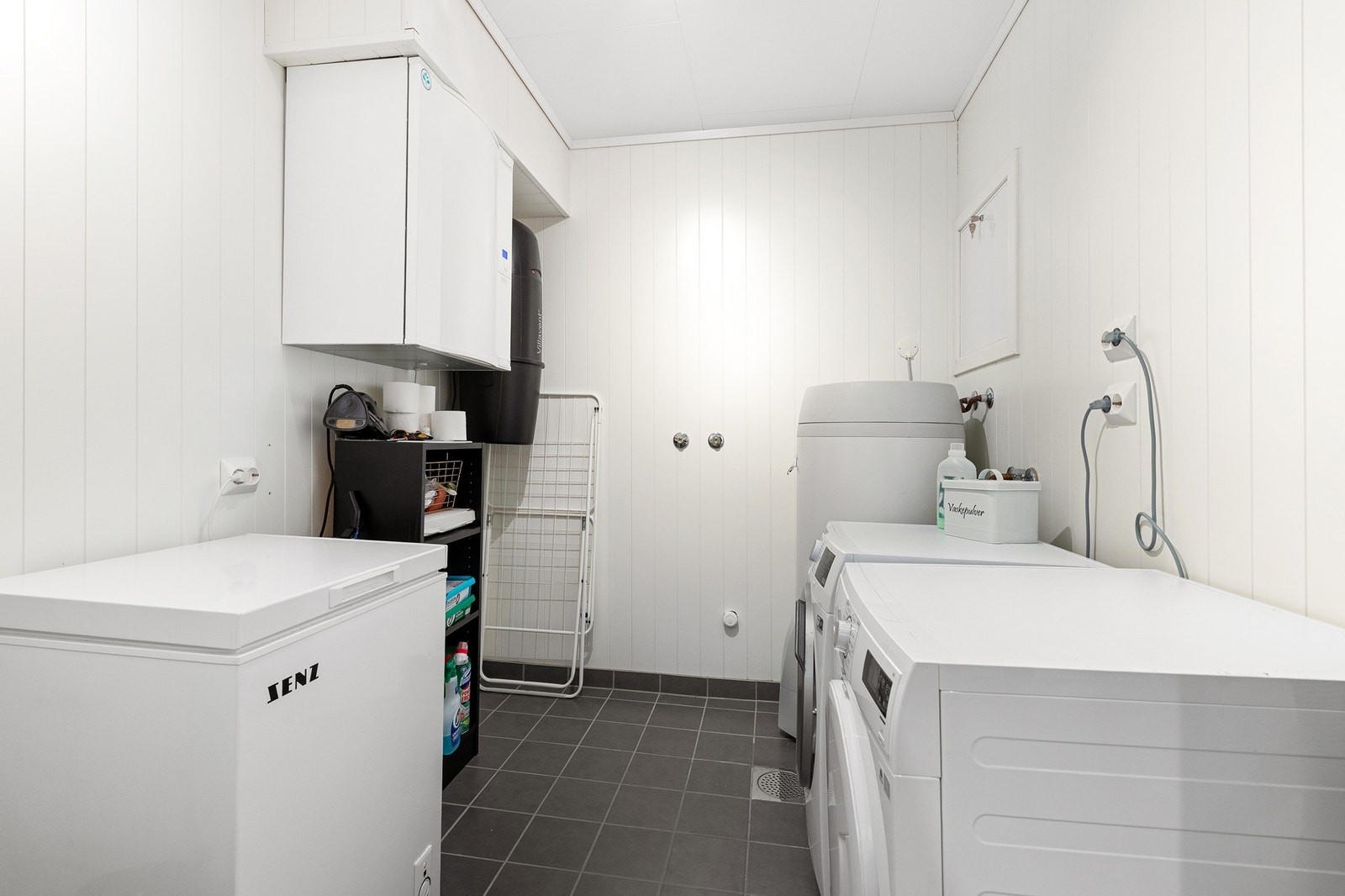 Vaskerom med flislagt gulv, opplegg for vaskemaskin og god plass til oppbevaring. Galleribilde