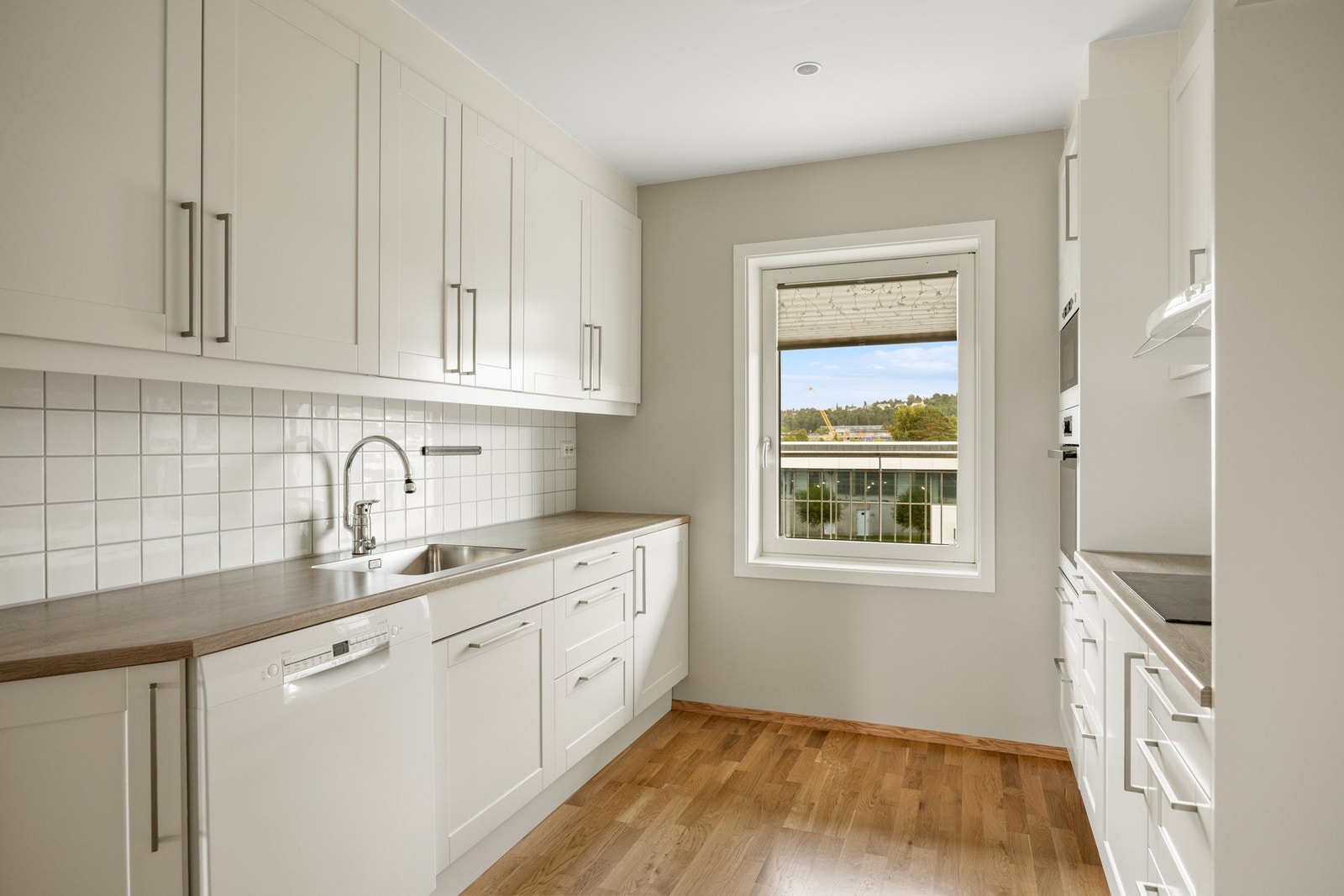 Lyst og pent kjøkken med integrerte hvitevarer. Galleribilde