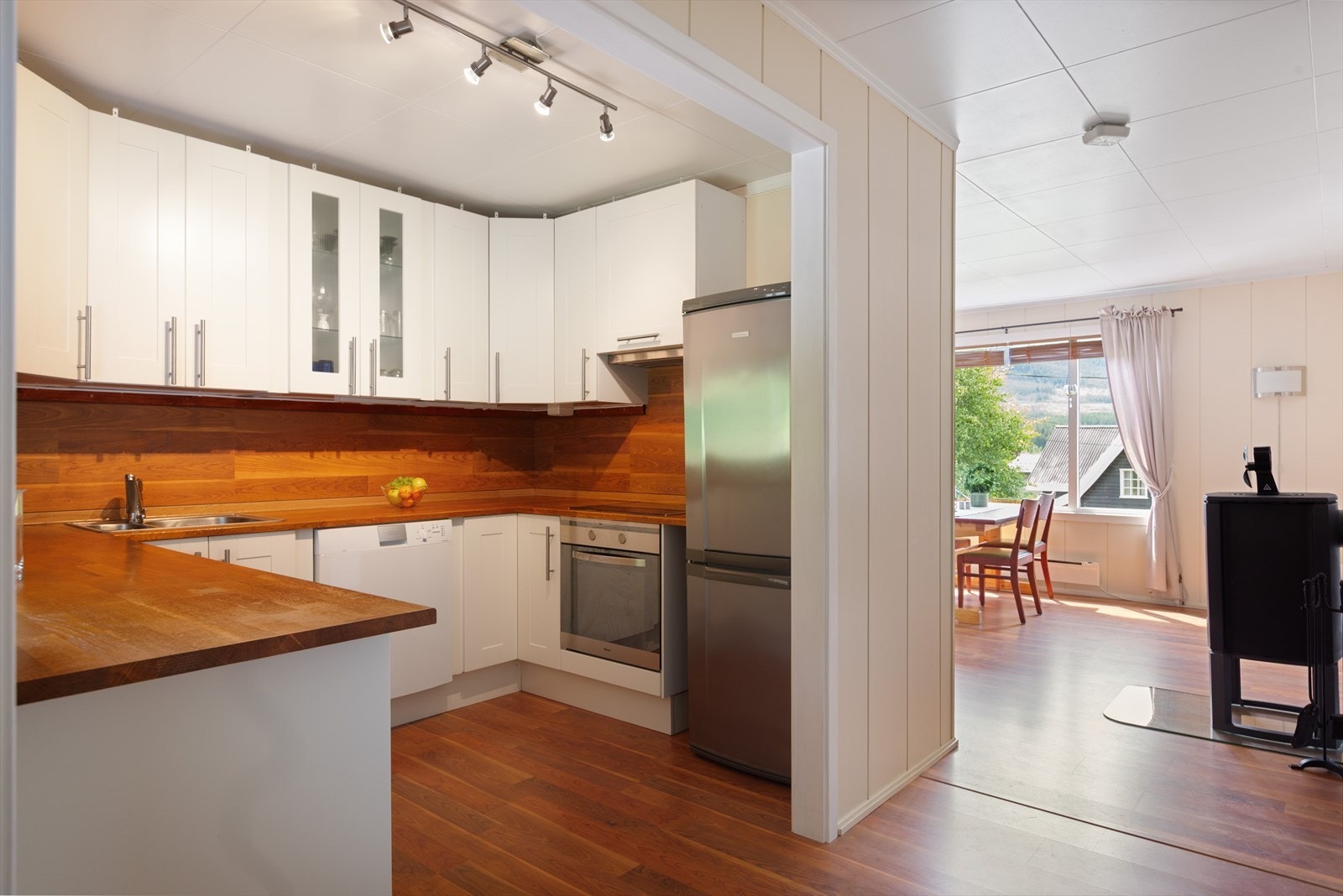 Fra stue/gang er det delvis åpent inn til kjøkken med innredning i malte folierte plater med over- og underskap. Galleribilde