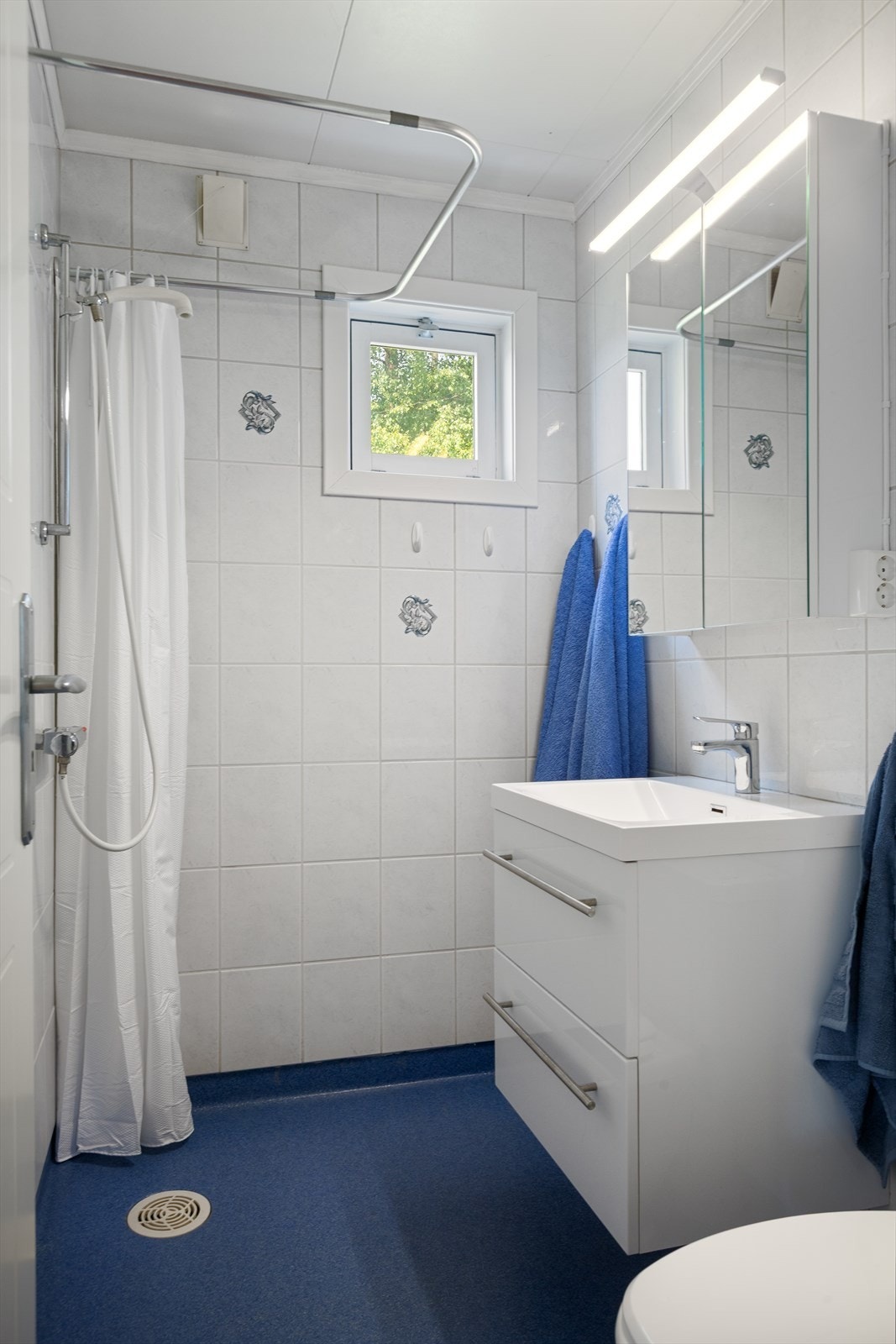 På badet er det lyse, flislagte vegger og belegg på gulv. Badet ble oppusset i 2000 og varmes opp av strålevarmer. Galleribilde