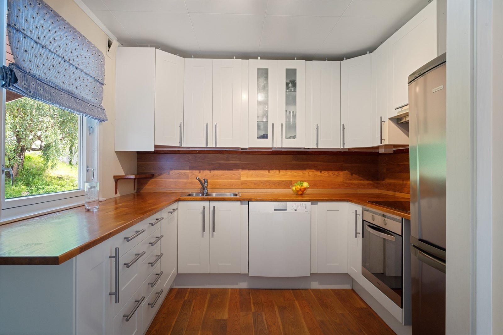 Kjøkkeninnredningen har heltre benkeplate i eik og oppvaskkum med kran av stål. På ett av overskapene er det glassdører. Galleribilde