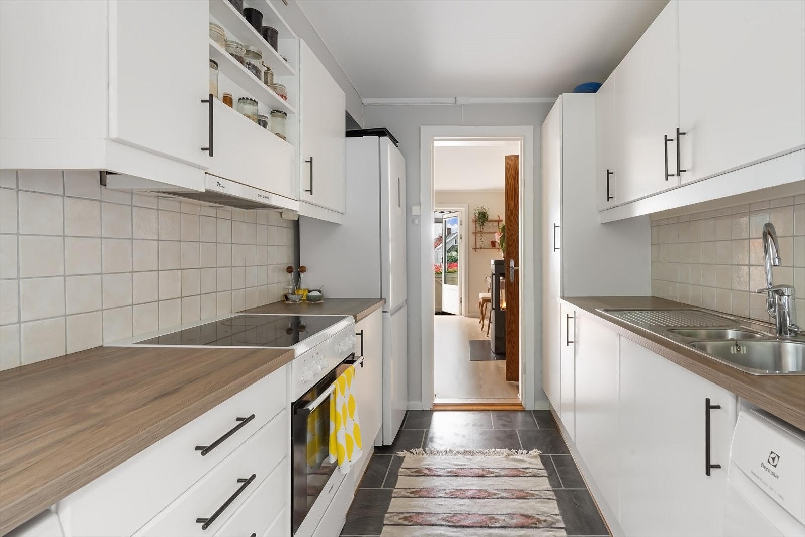 Slette fronter, belysning under overskap, fliser på vegg over benkeskap og laminat benkeplate. Galleribilde