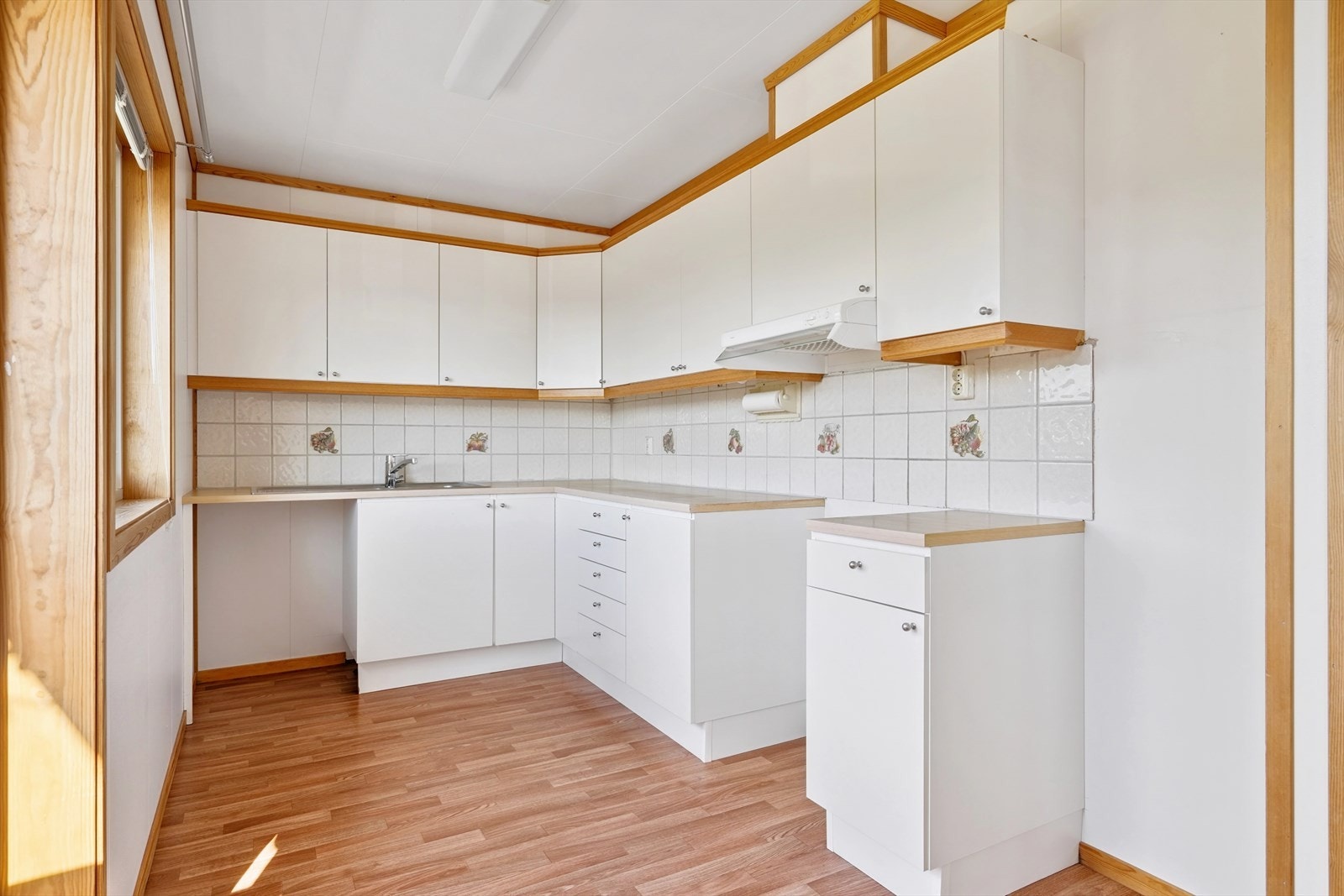 Kjøkkenet er godt tilrettelagt med overskap i hele kjøkkenlengden og flislagt vegg over benkeplaten Galleribilde