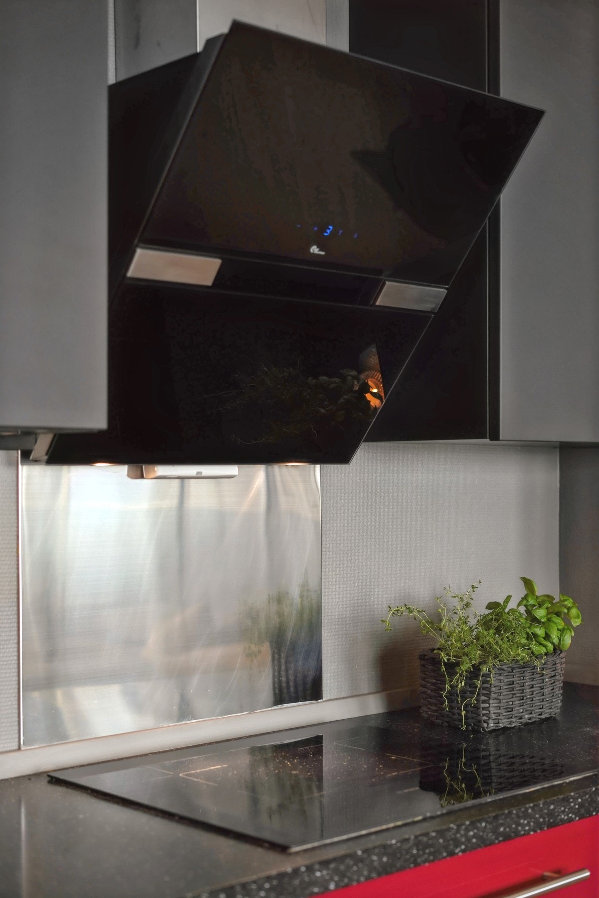 Vannbestandig plate på vegg bak induksjonstopp. Kjøkkenventilator med avtrekk ut. Galleribilde