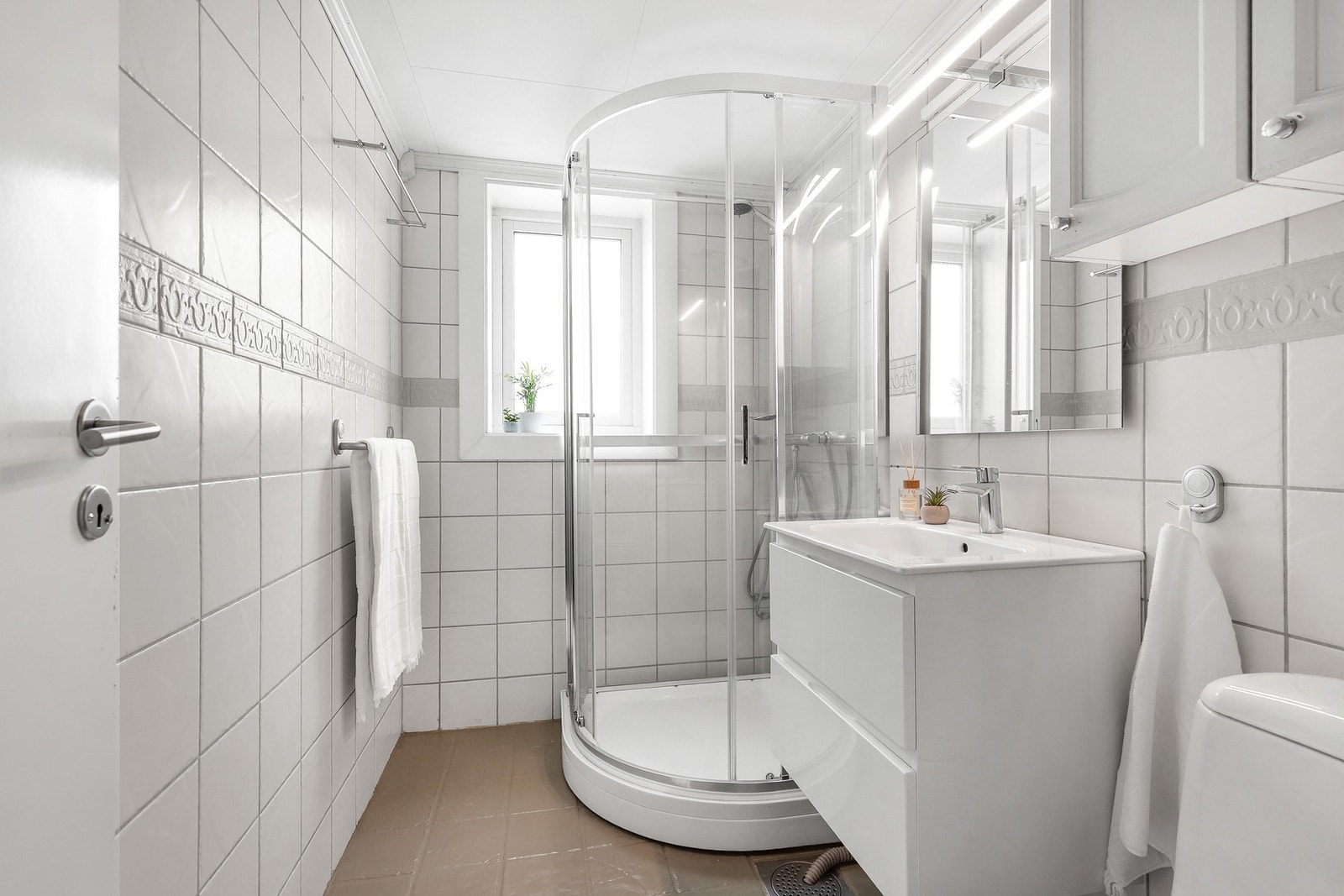 Helfliset bad med gulvvarme og innredet med gulvstående toalett, dusjkabinett og servantinnredning Galleribilde