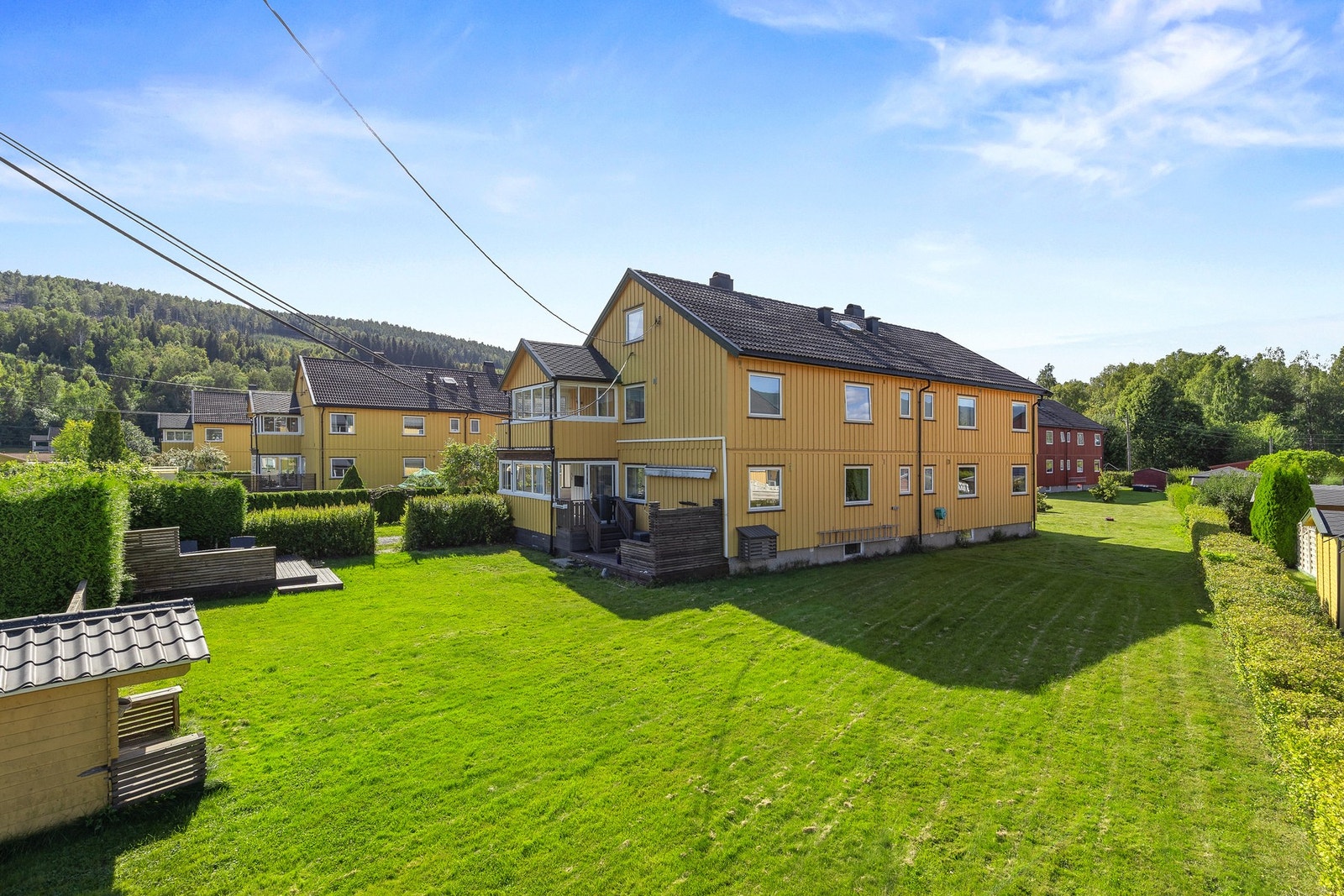 Tomten er pent opparbeidet med gressplen, hekk, trivelig platting, lekestue og diverse beplantning Galleribilde